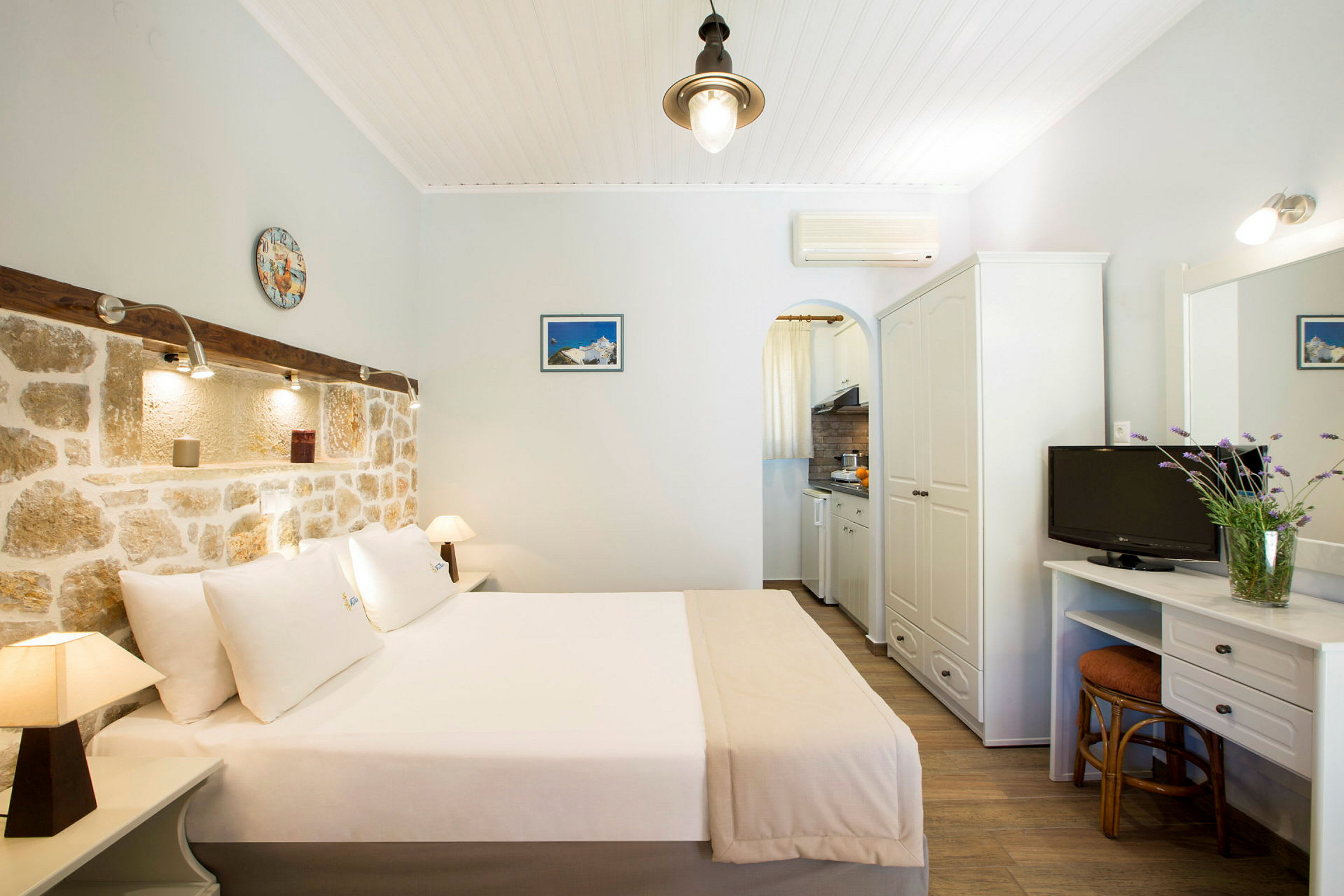 Hotelværelse med dobbeltseng, murstensvæg og lille køkkenområde. (AI-genereret tekst)