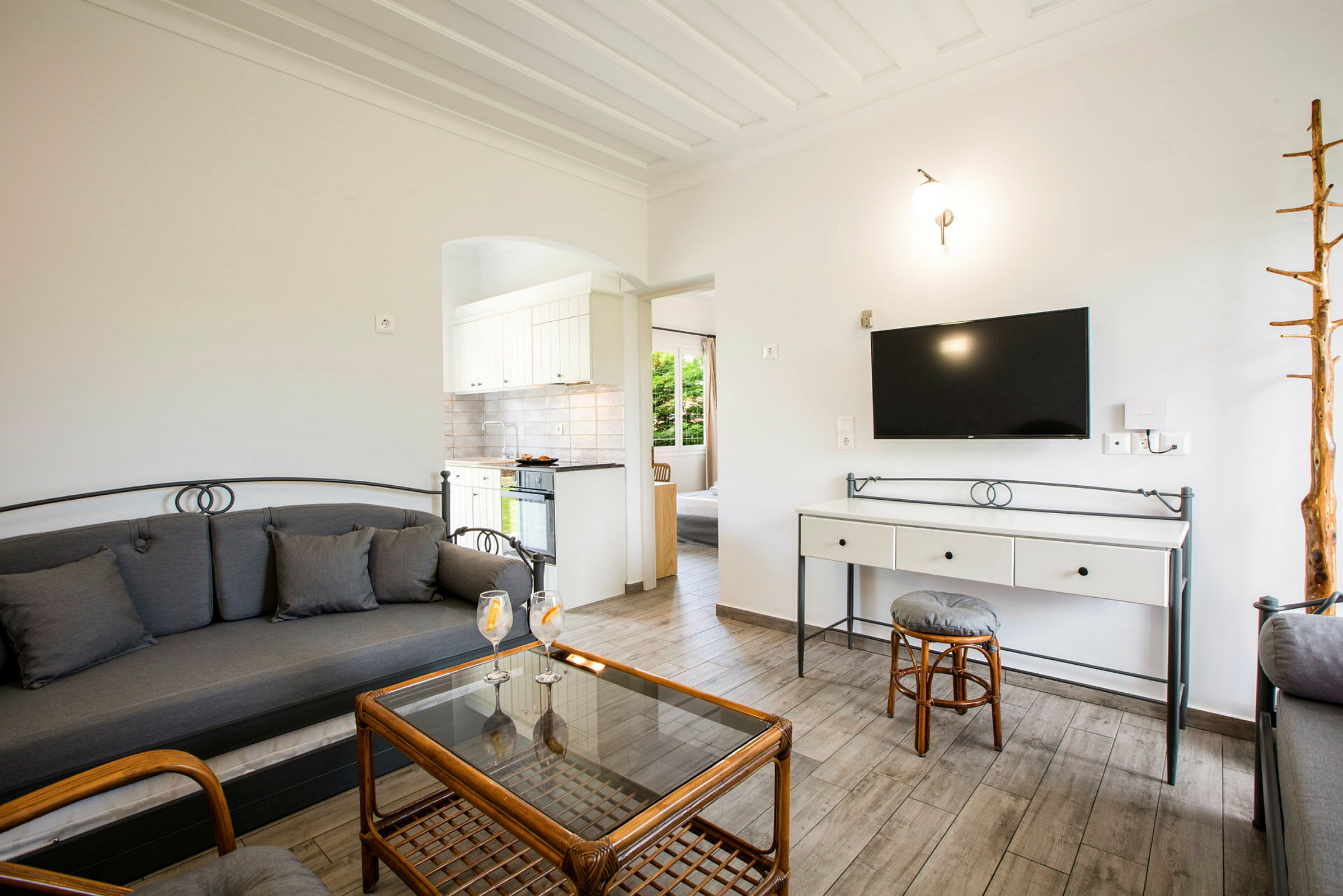 Stue med sofa, glasbord og et tv på væggen. (AI-genereret tekst)