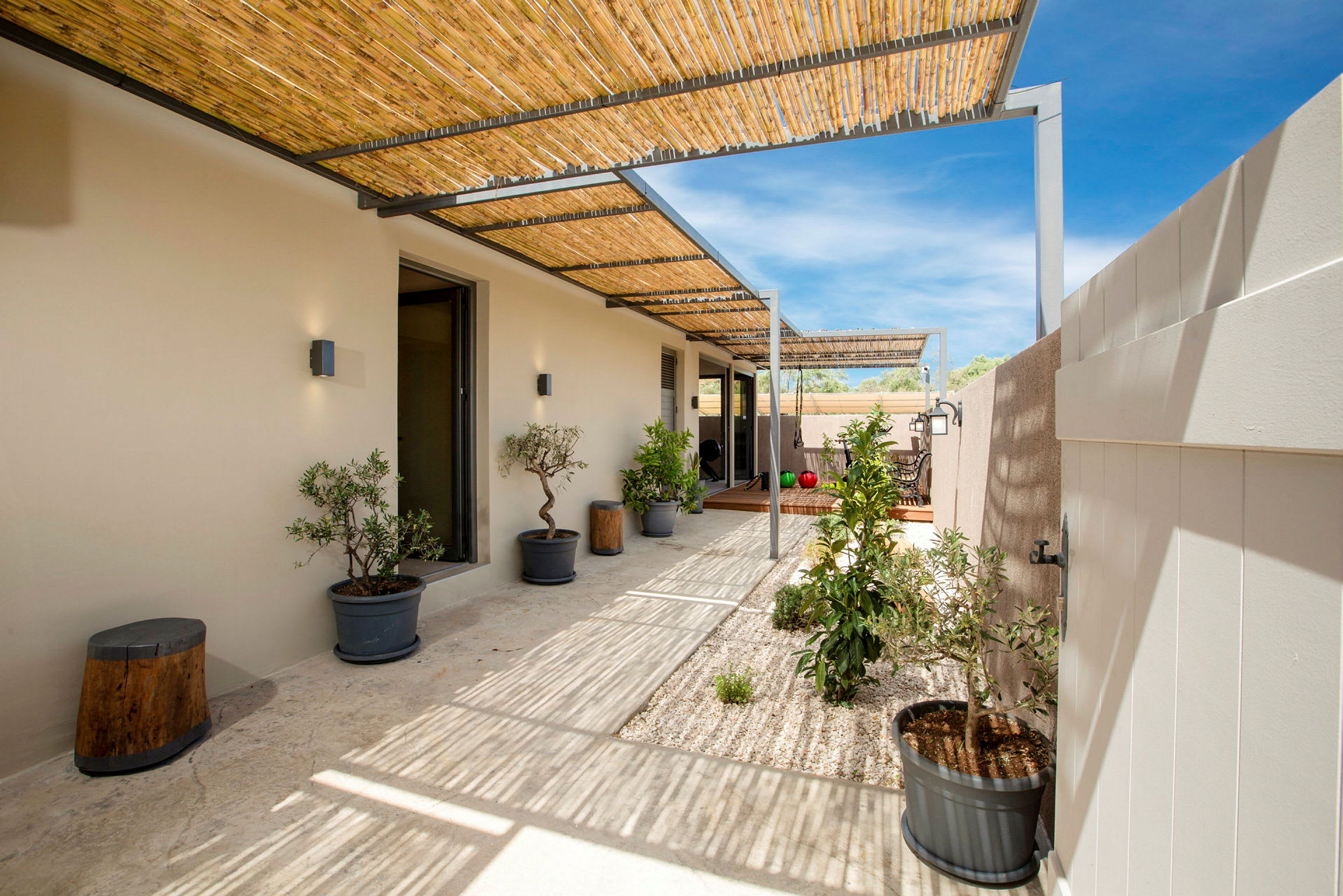 En udendørs terrasse med pergola og planter i potter. (AI-genereret tekst)