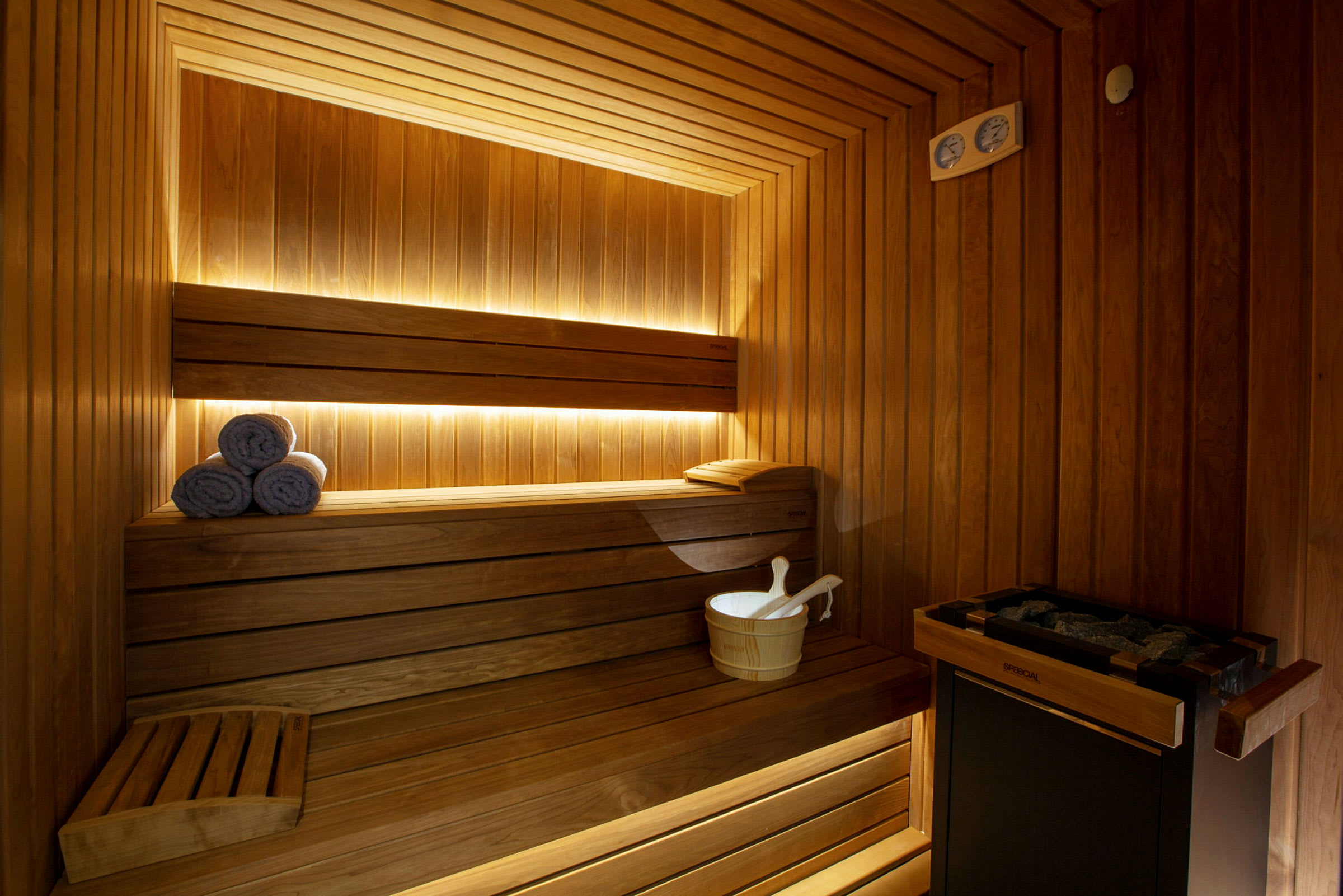 En brændefyret sauna med træpanel, bænk, en spand og ruller af håndklæder. (AI-genereret tekst)