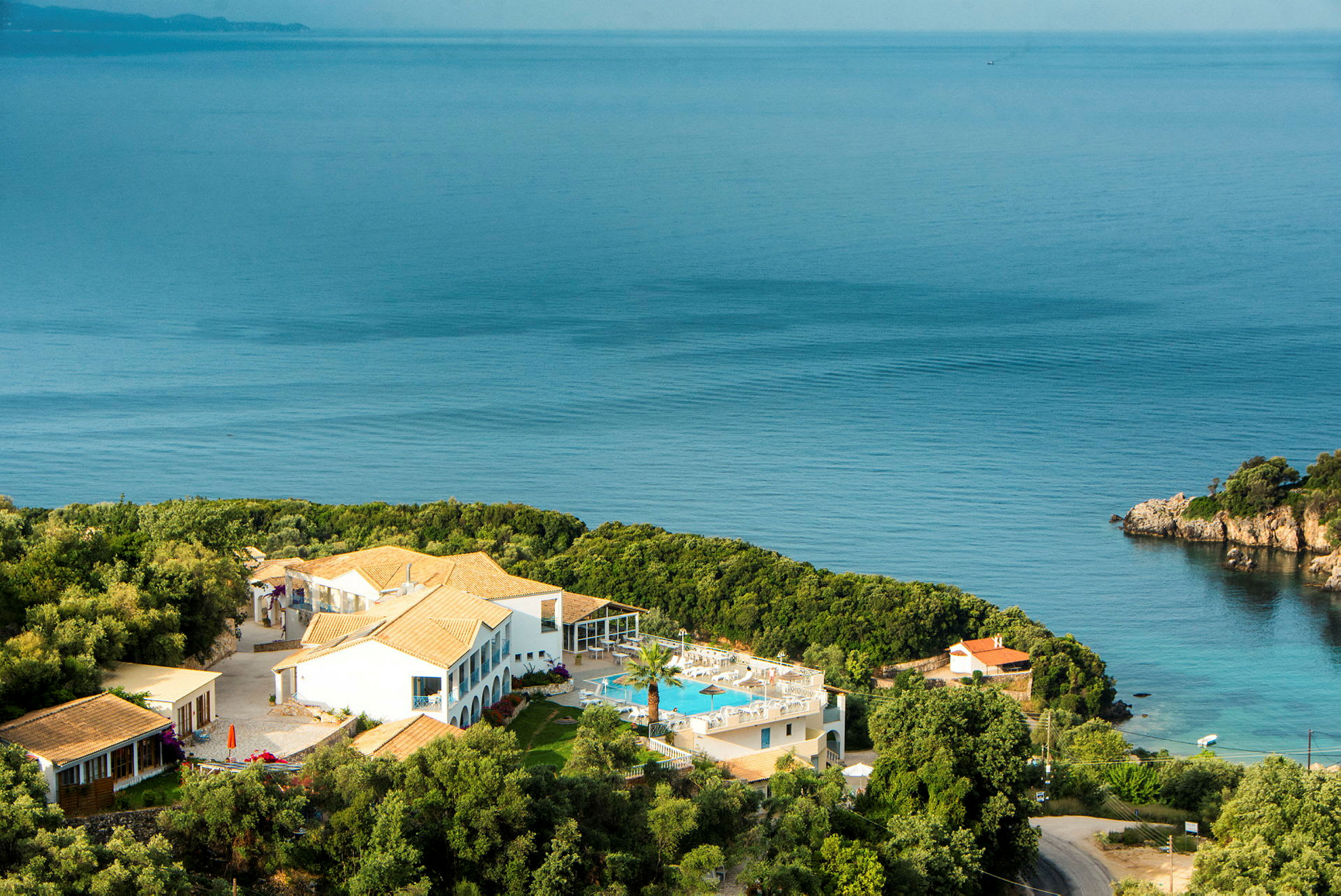 Hotelbygning med pool og omkringliggende grønt områder ved havet. (AI-genereret tekst)