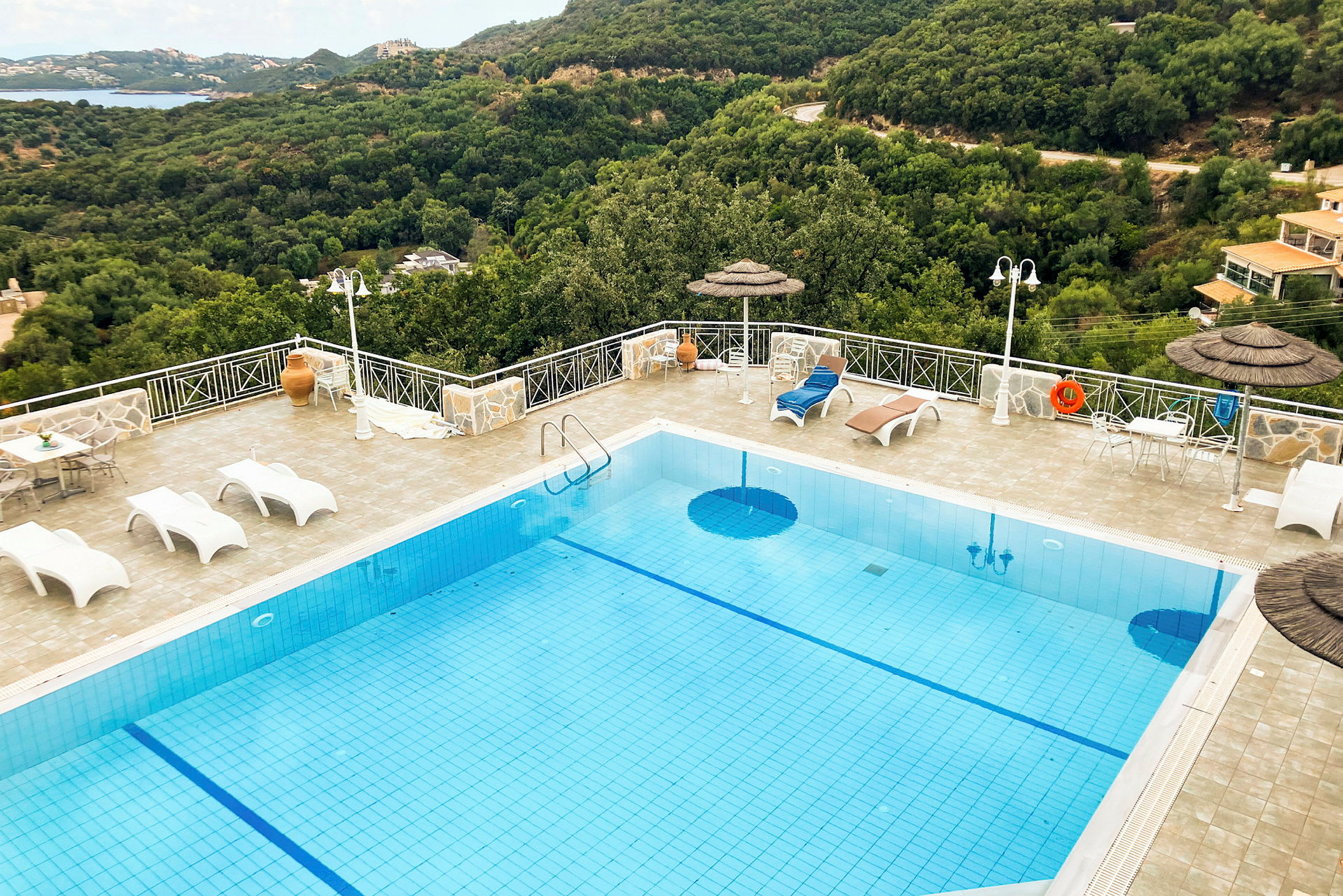 Swimmingpool med liggestole og udsigt over frodige bakker. (AI-genereret tekst)