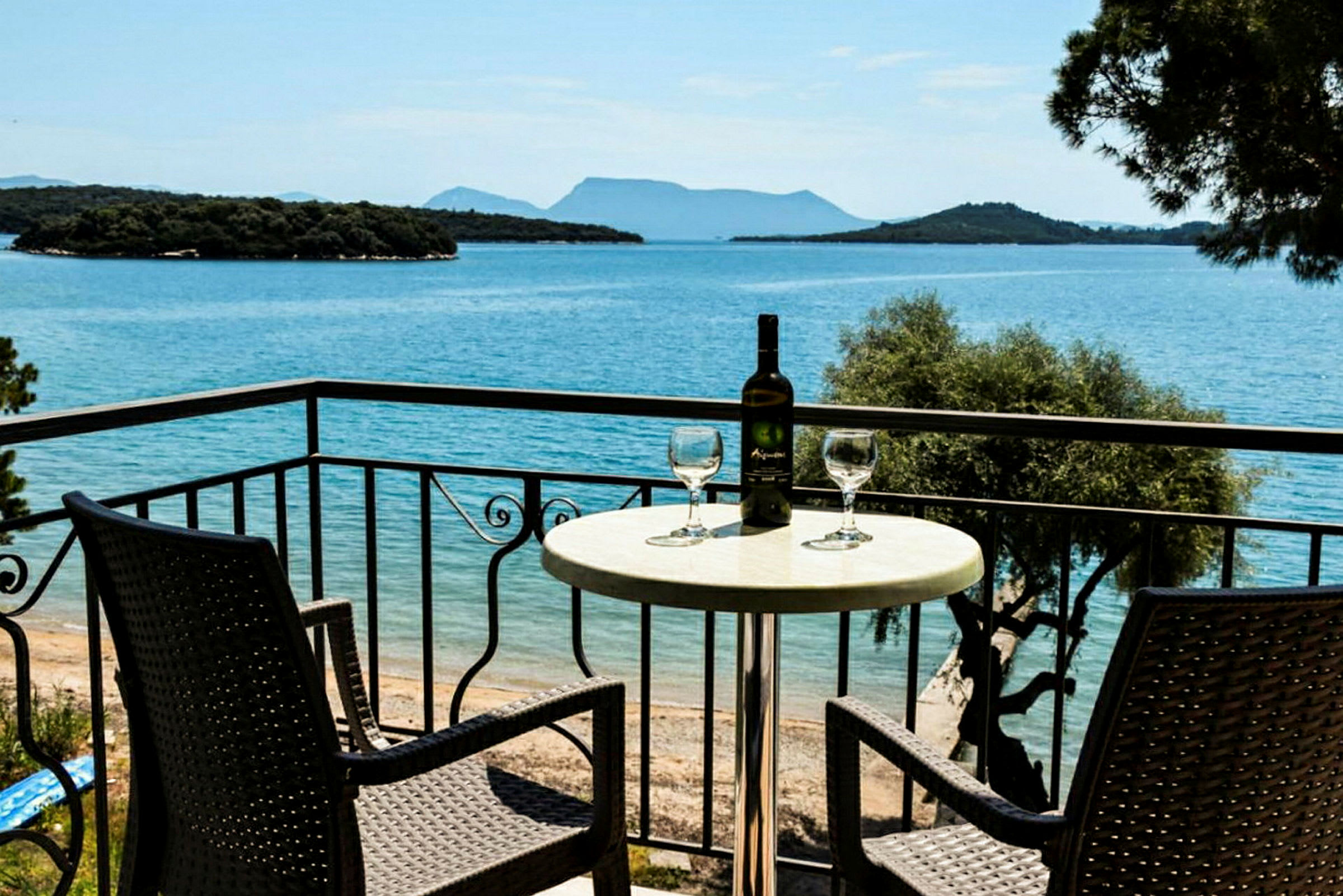 To stole og et bord med en vinflaske og glas på en altan med udsigt over havet. (AI-genereret tekst)