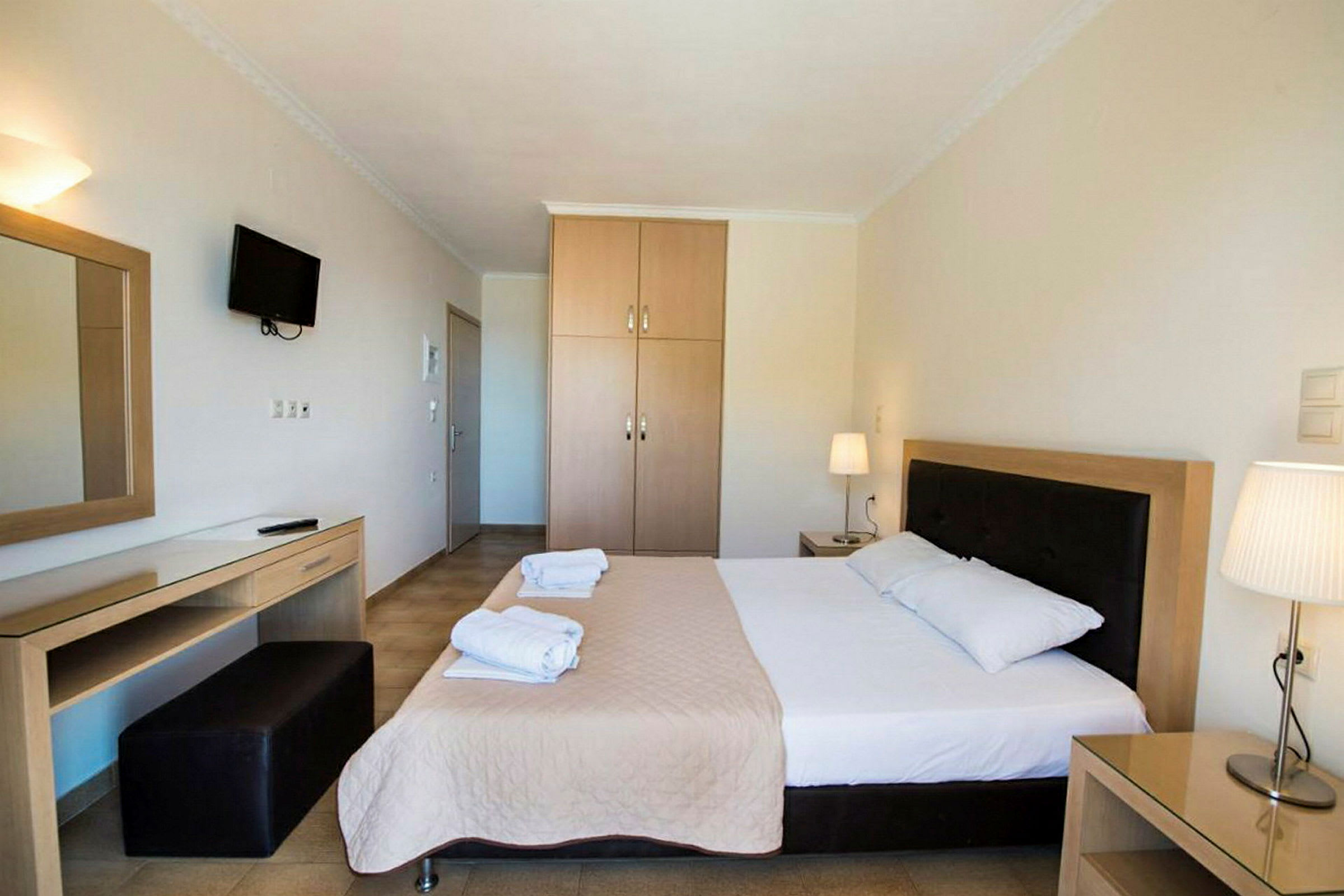 Hotelværelse med en dobbeltseng, natbord, garderobe og skrivebord. (AI-genereret tekst)