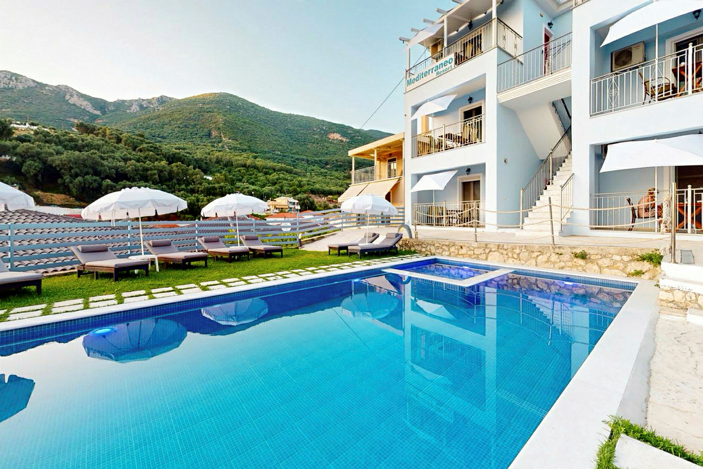 Udendørs swimmingpool foran hotel med liggestole og parasoller. (AI-genereret tekst)