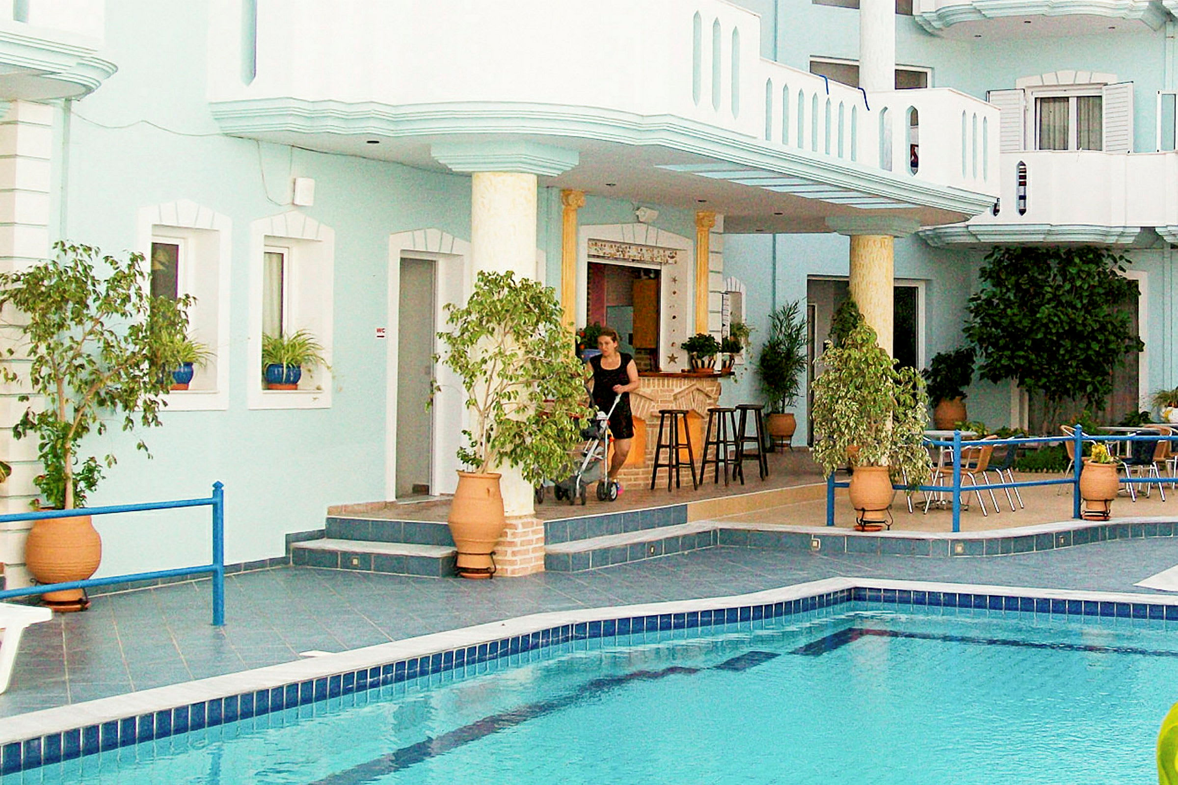 Poolområde ved et hotel med planter og en terrasse. (AI-genereret tekst)