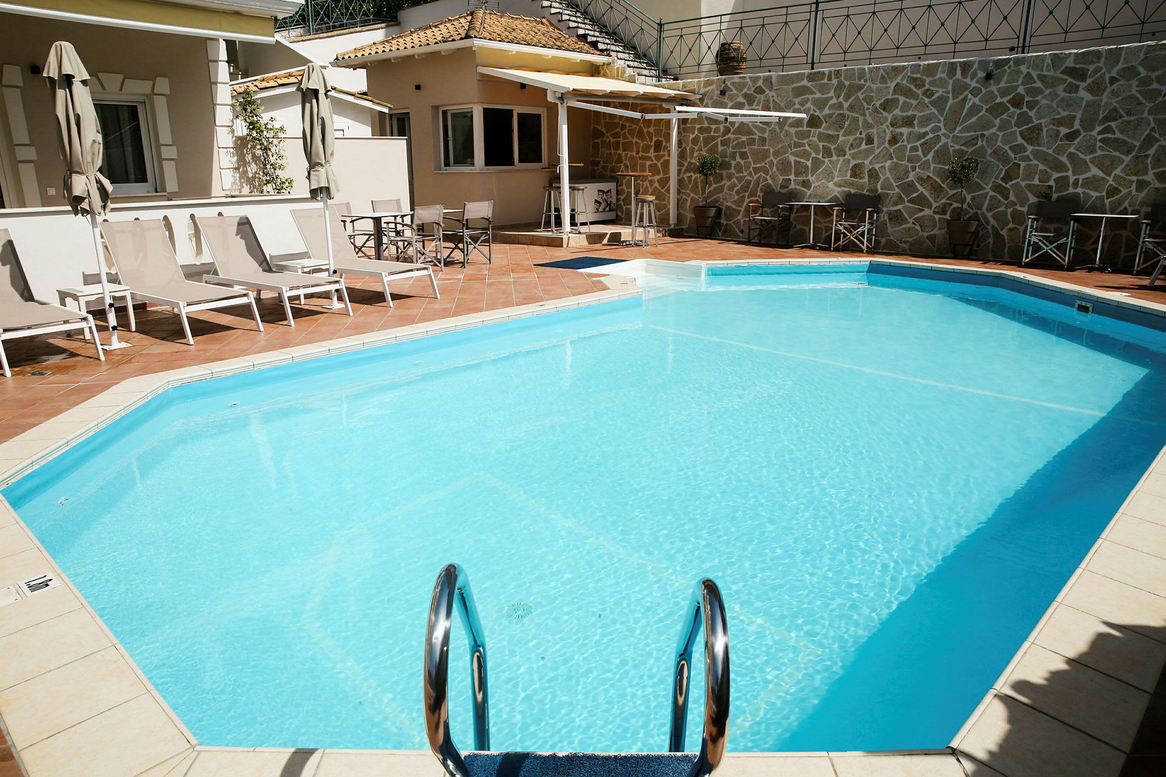 Udendørs pool med liggestole og parasoller ved siden af. (AI-genereret tekst)