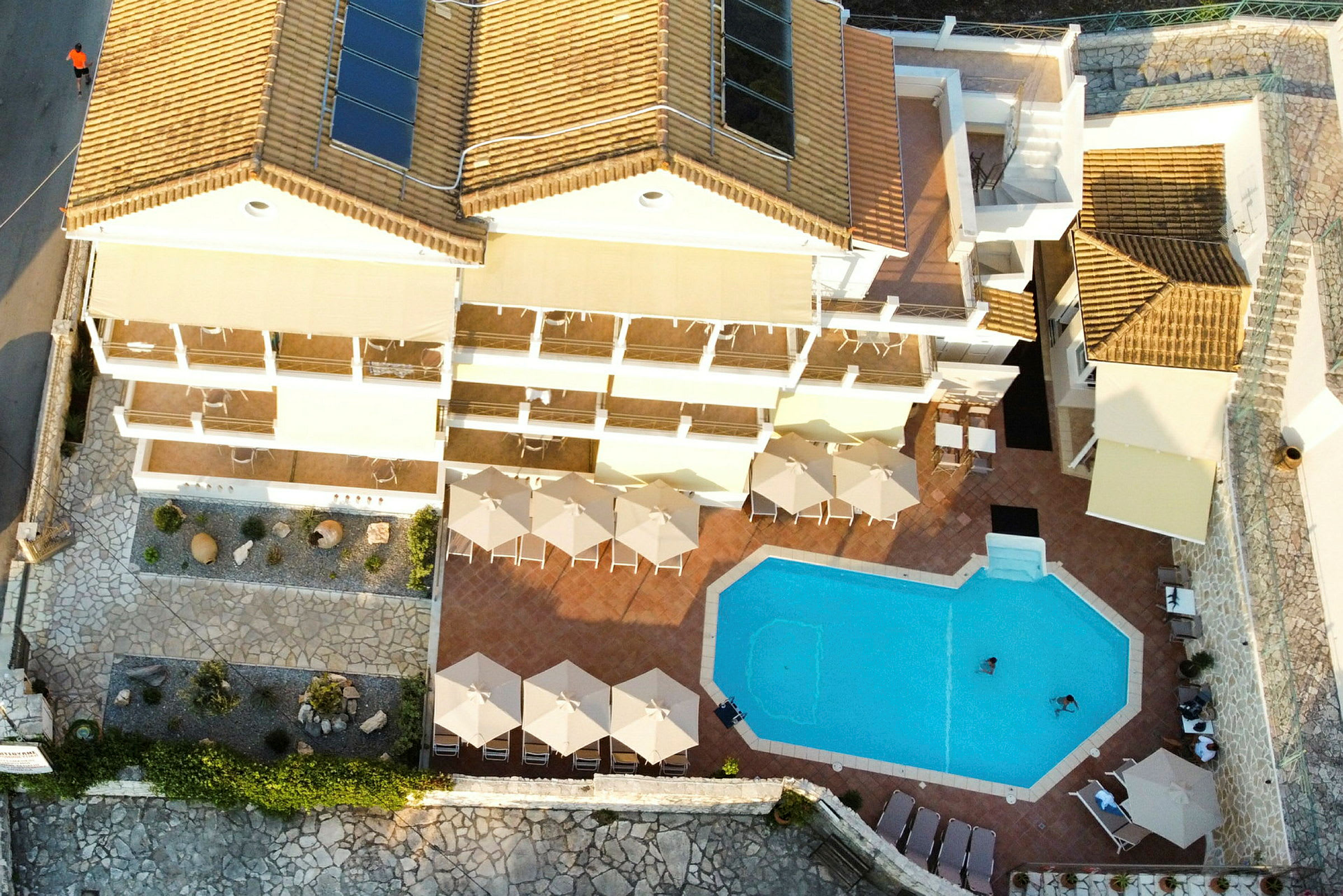 Et fugleperspektiv af et hotelområde med en pool og parasoller. (AI-genereret tekst)