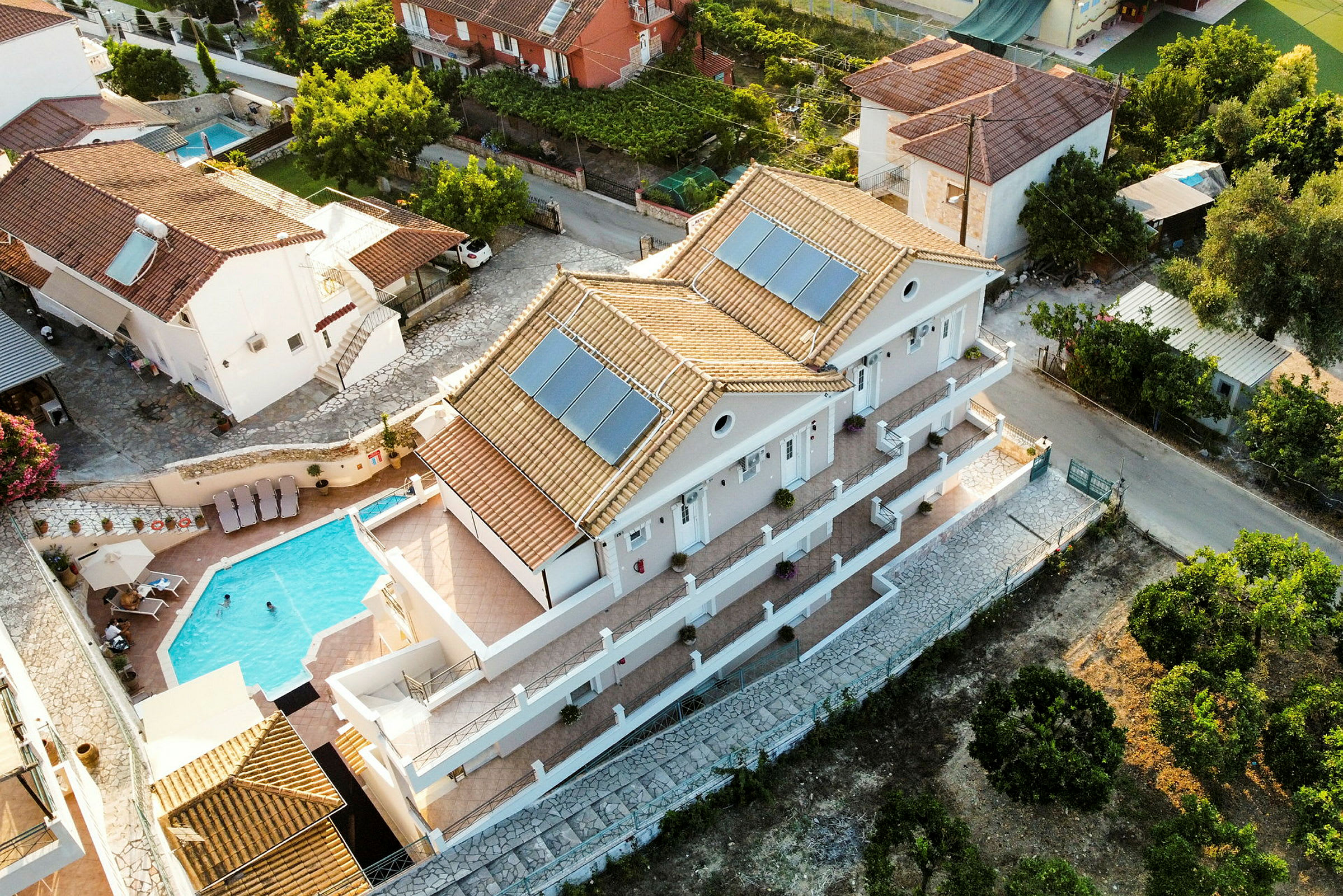 Luftfoto af villa med pool og omkringliggende huse. (AI-genereret tekst)