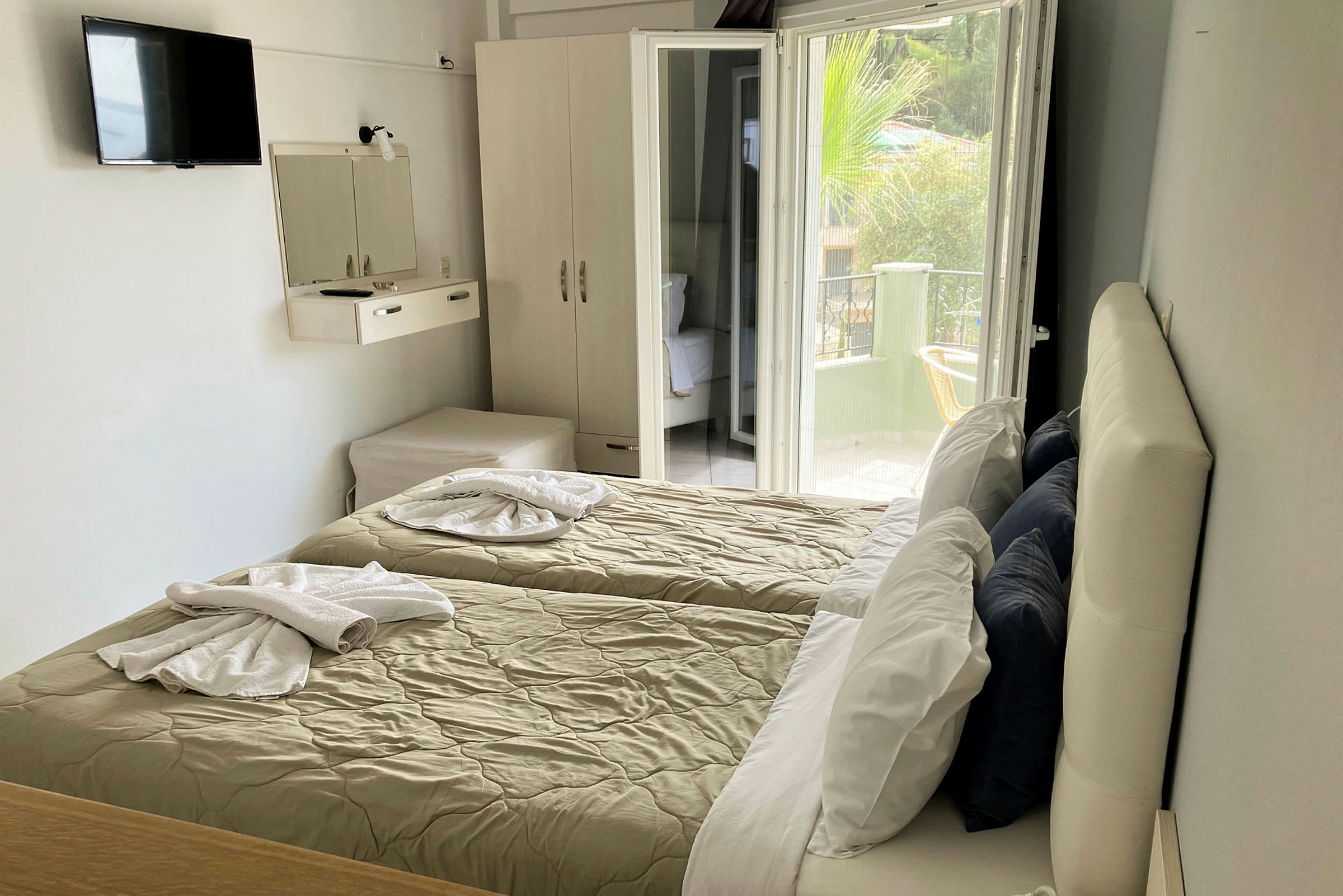 Hotelværelse med to enkeltsenge, garderobe og åben altandør. (AI-genereret tekst)