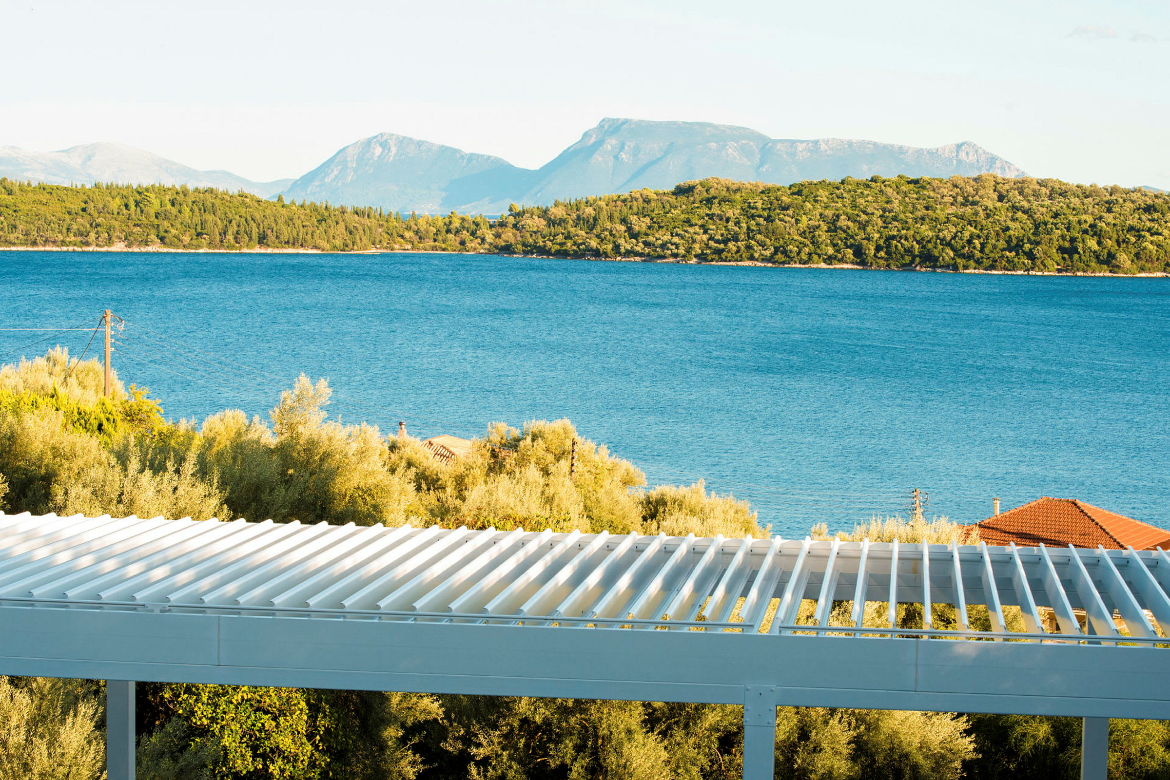 Udsigt over havet med træer og en terrasse i forgrunden. (AI-genereret tekst)