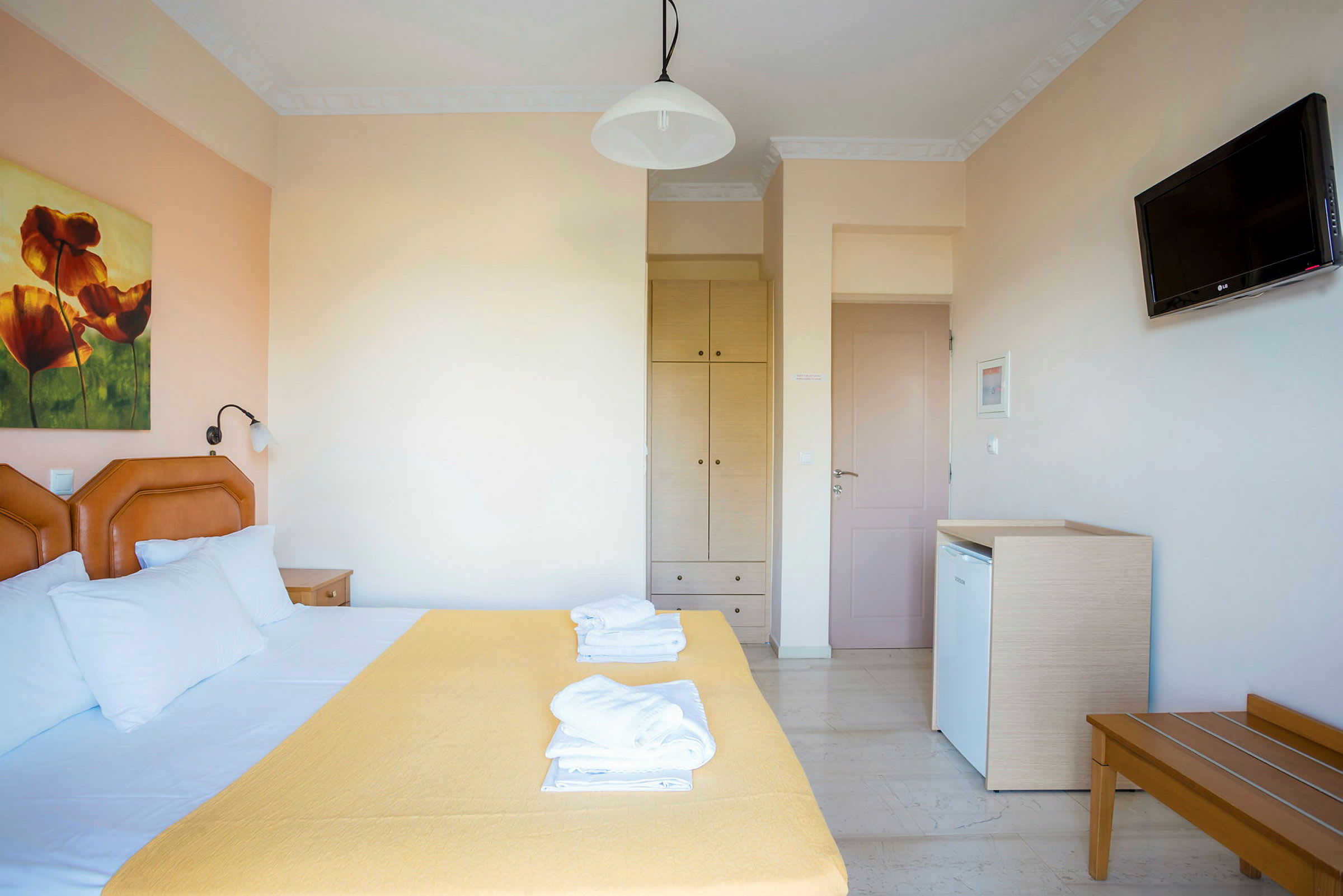 Hotelværelse med dobbeltseng, et gult sengetæppe og maleri på væggen. (AI-genereret tekst)