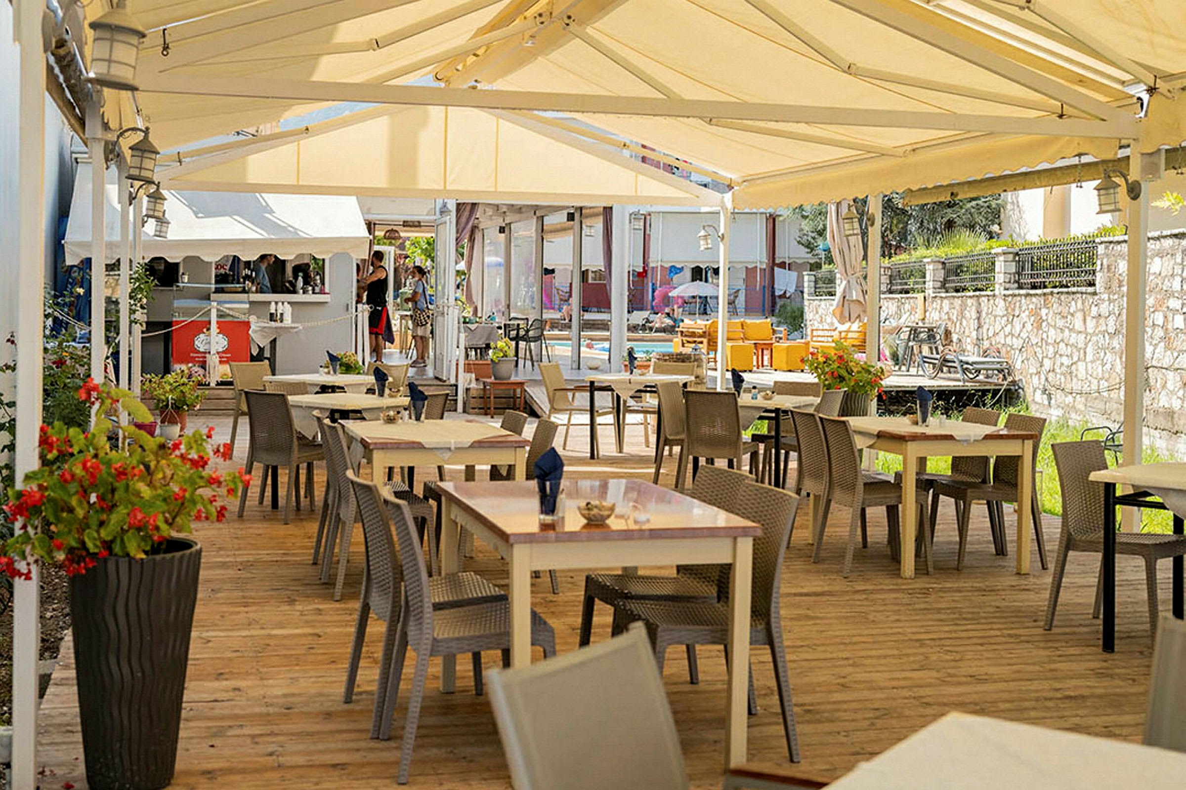 Udendørs restaurant med borde og stole under et telt. (AI-genereret tekst)