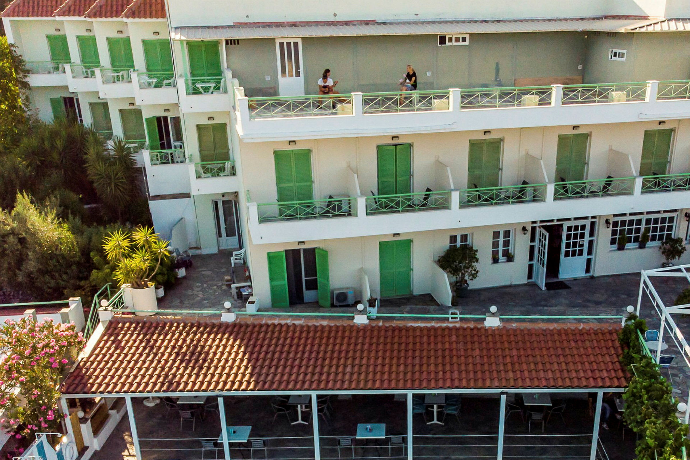 Hotellets facade med altaner og udendørs terrasse. (AI-genereret tekst)