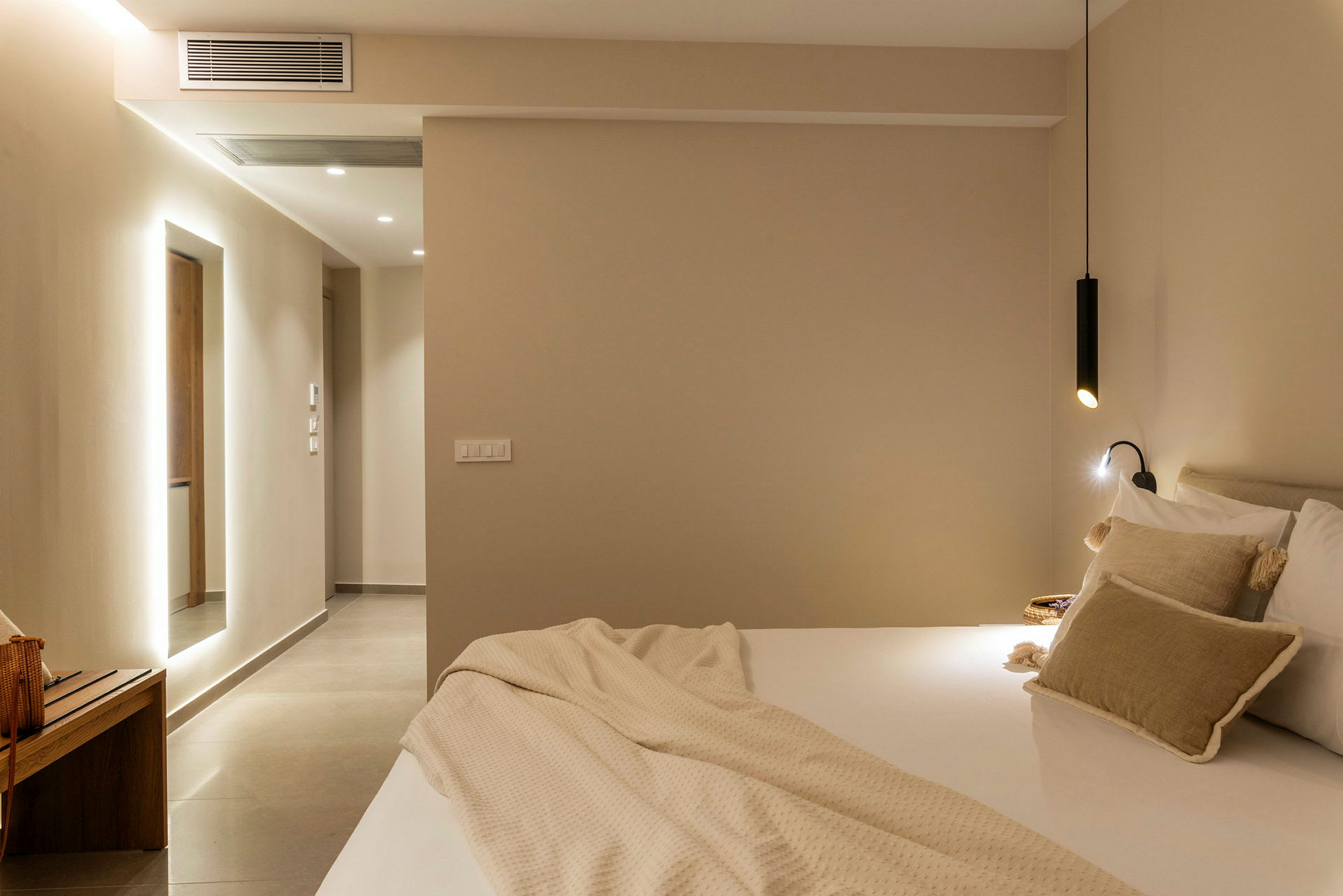 Et moderne hotelværelse med seng og bløde puder samt minimalistisk belysning. (AI-genereret tekst)