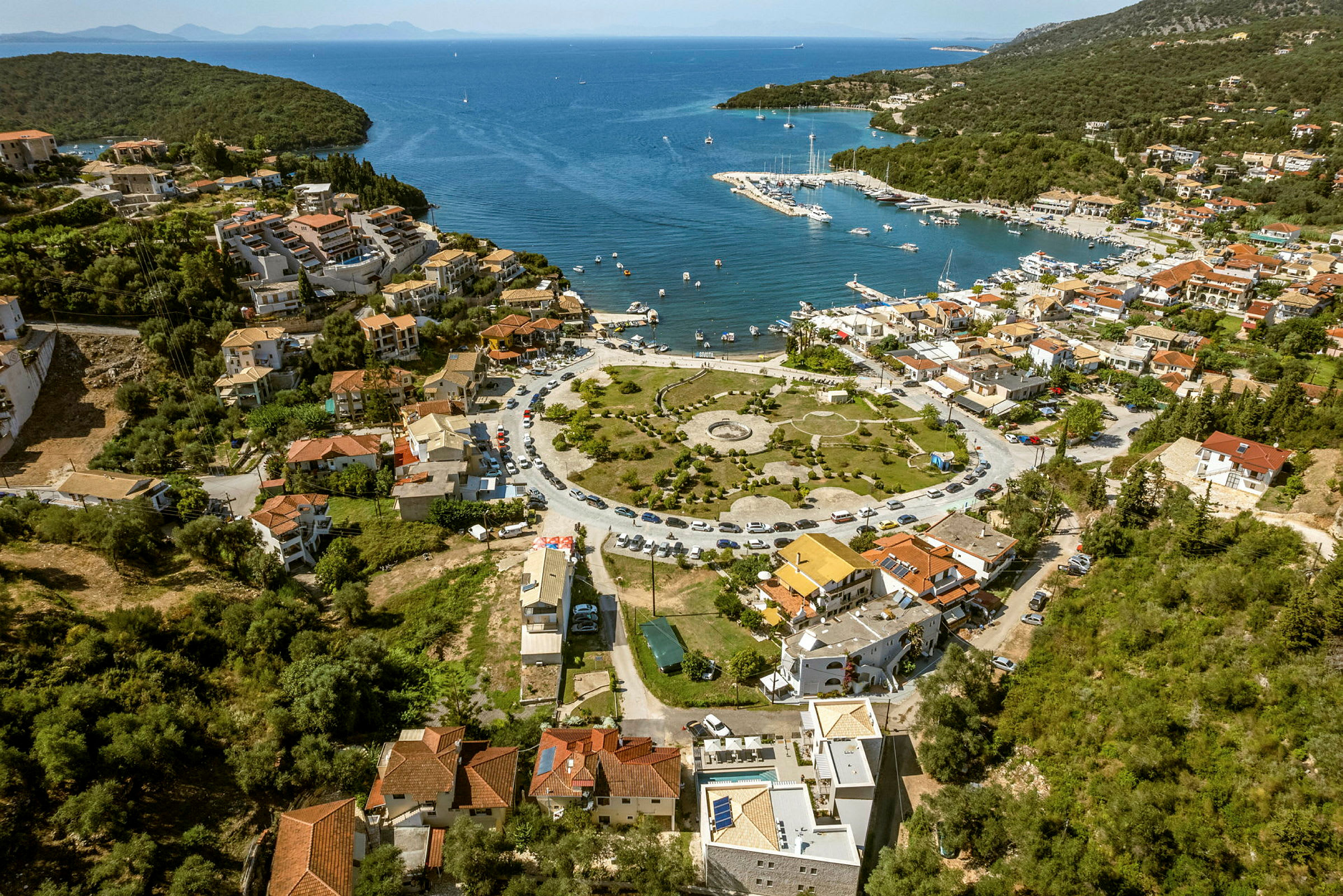 Luftfoto af en kystby med en lystbådehavn ved et blåt hav. (AI-genereret tekst)