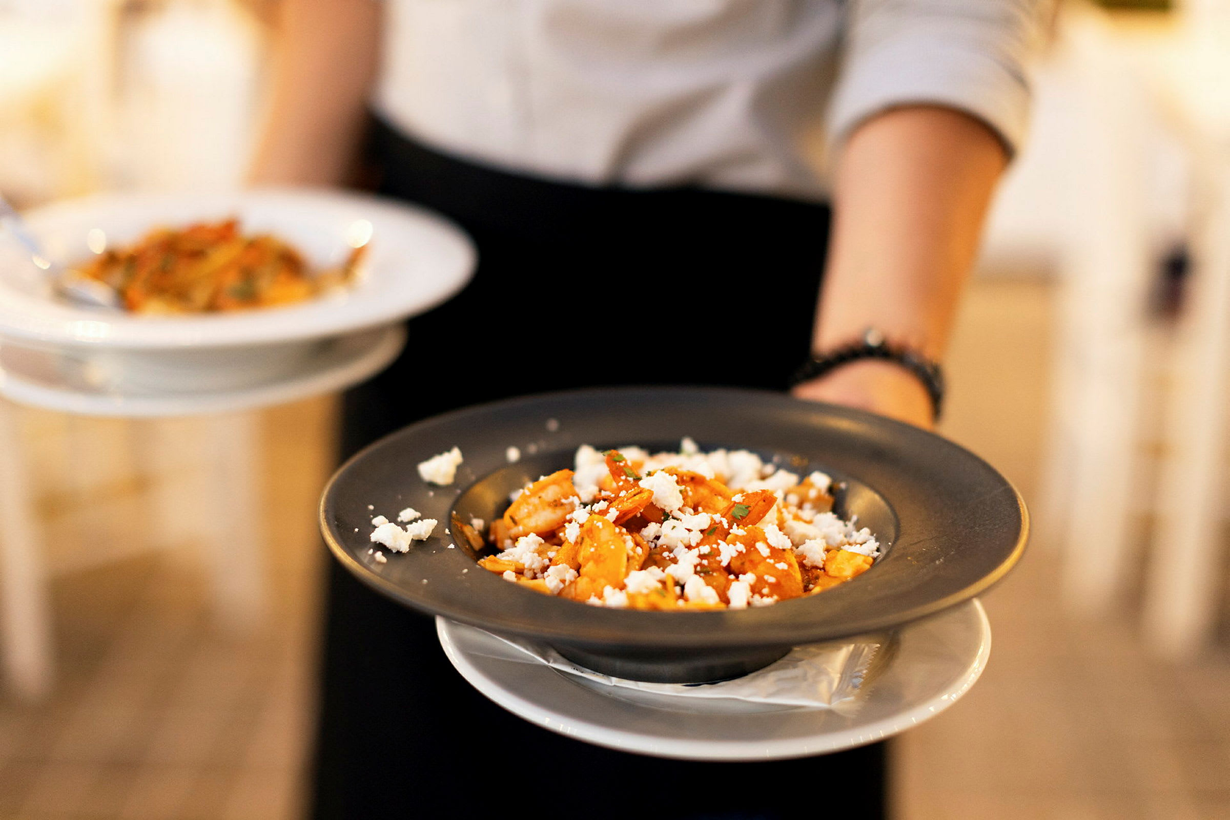 En person holder to tallerkener med pasta. (AI-genereret tekst)