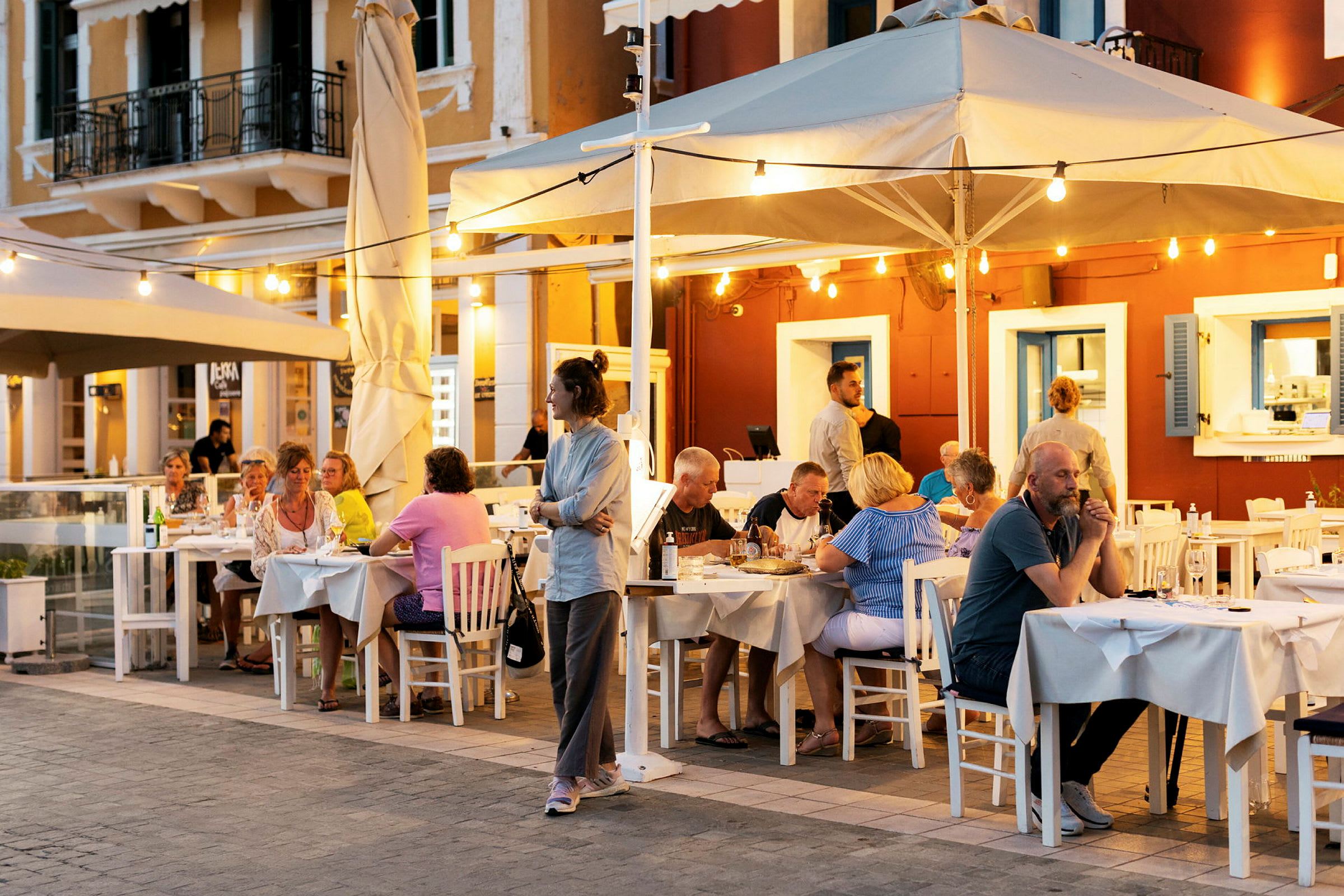 Udendørsrestaurant med gæster siddende ved borde om aftenen. (AI-genereret tekst)