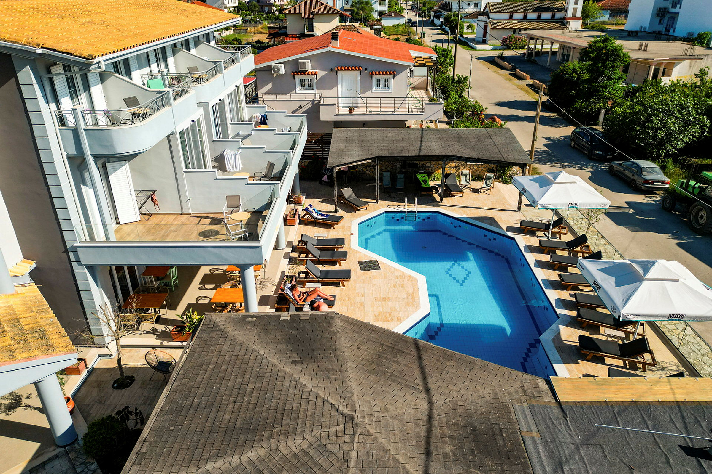 Et hotel med en udendørs pool omgivet af liggestole og parasoller samt en balkon med siddepladser. (AI-genereret tekst)