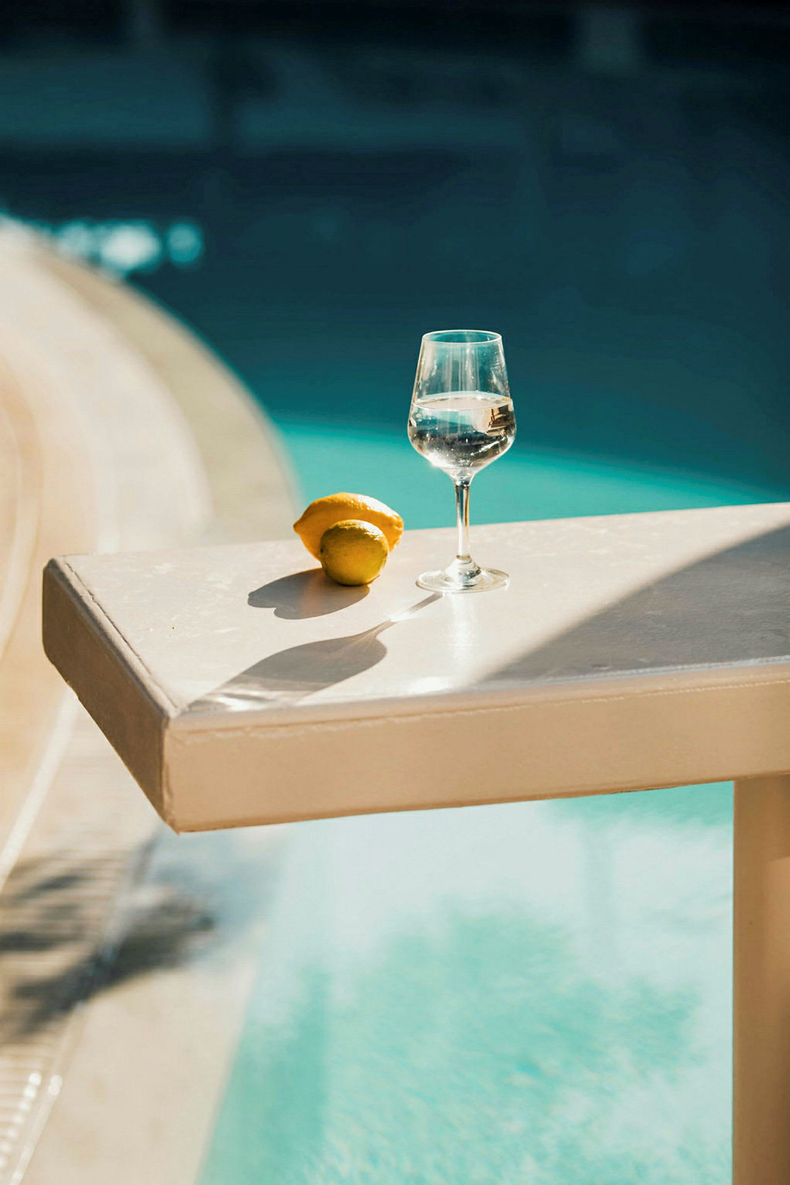 Et glas med vand står på et bord tæt på en pool med et citruspunkt ved siden af. (AI-genereret tekst)