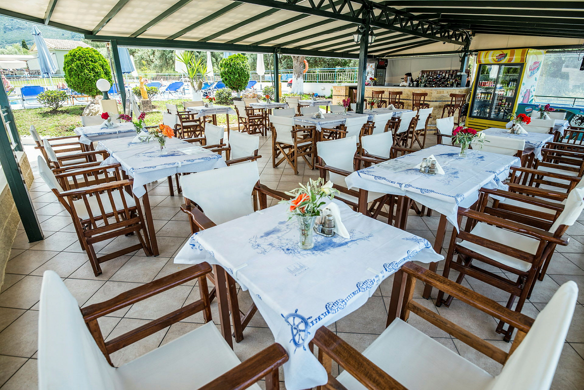 Udendørs restaurantområde med borde og stole samt dekorationer. (AI-genereret tekst)