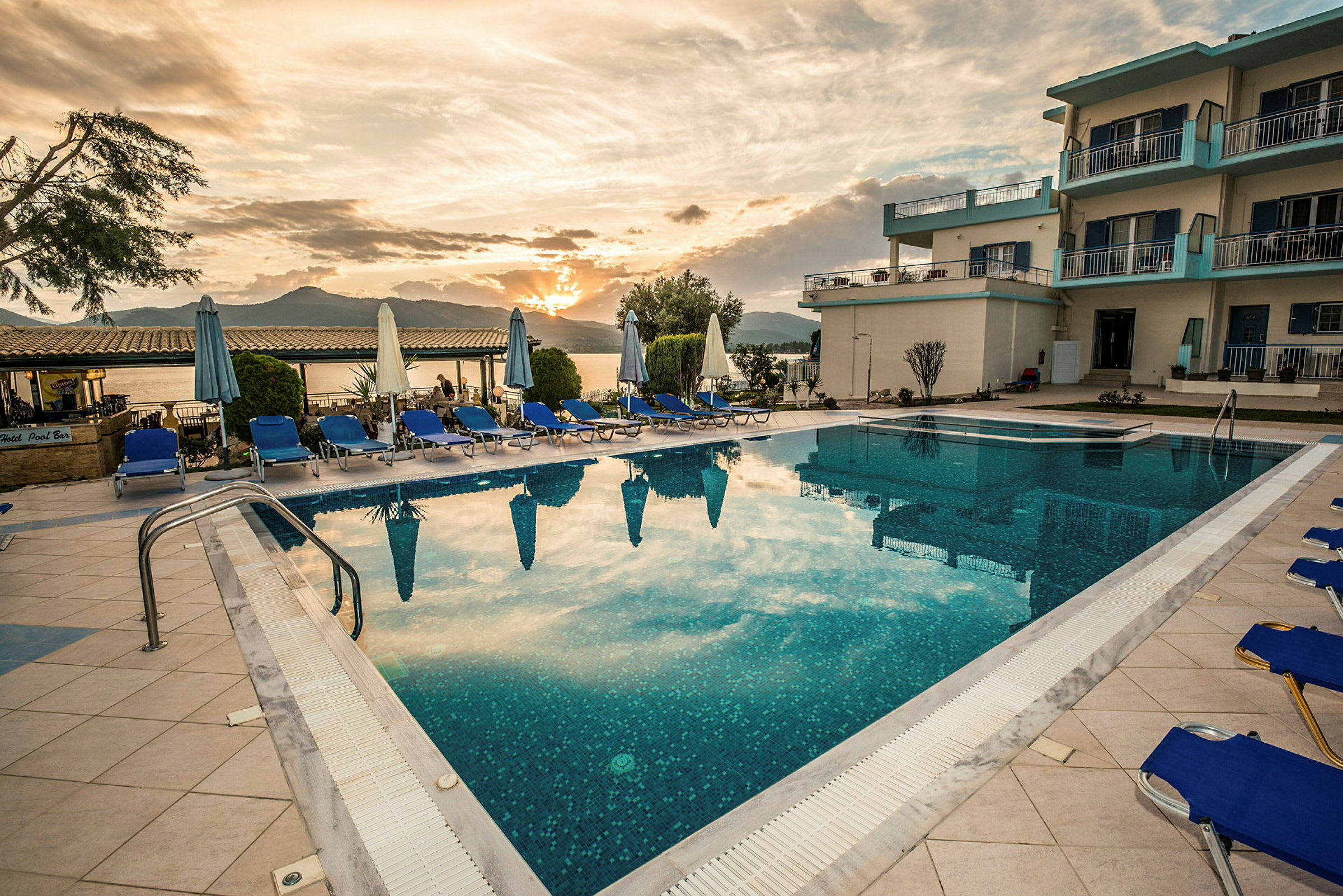 Udendørs swimmingpool omgivet af liggestole ved solnedgang. (AI-genereret tekst)