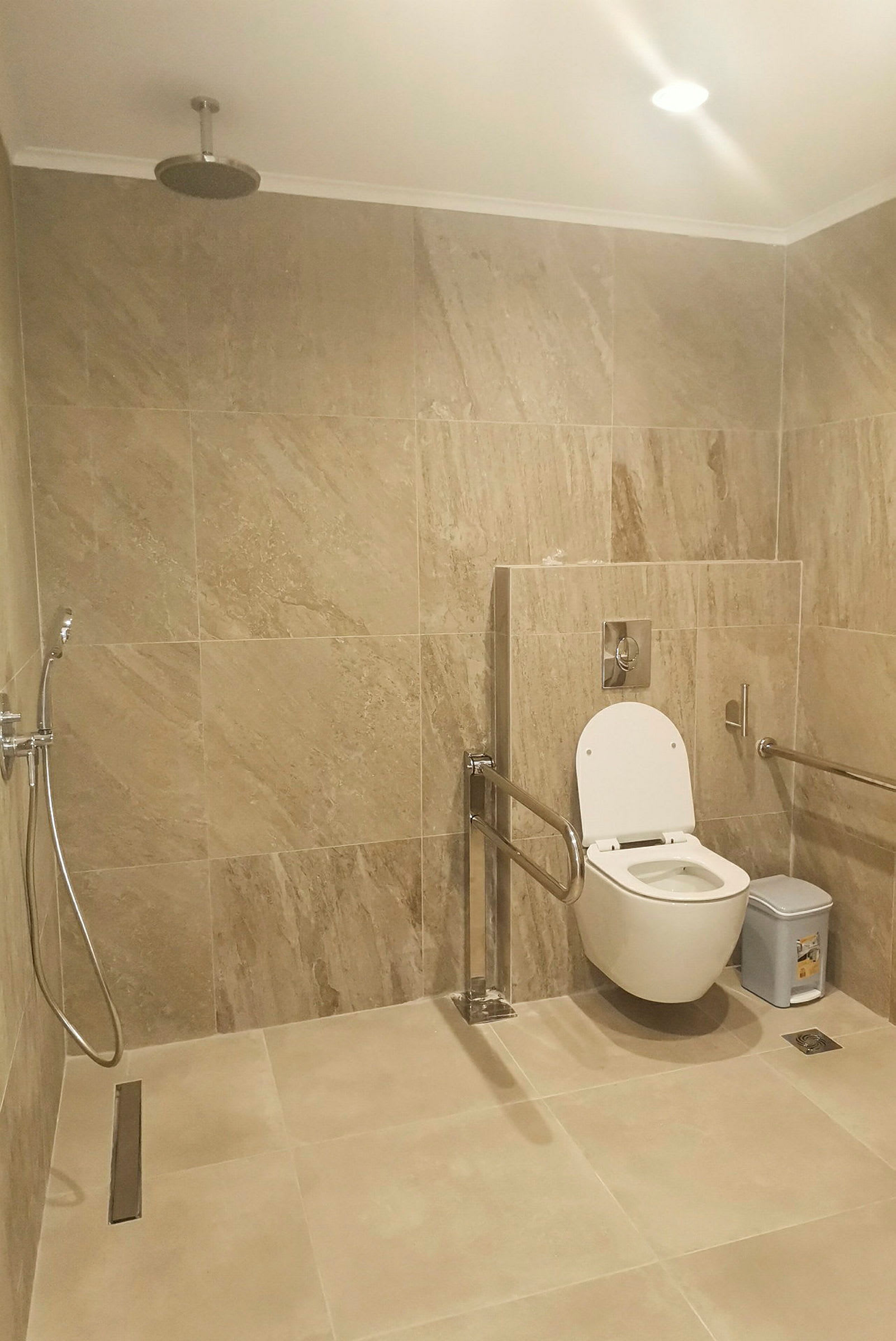 Handicapvenligt badeværelse med bruser og toilet. (AI-genereret tekst)