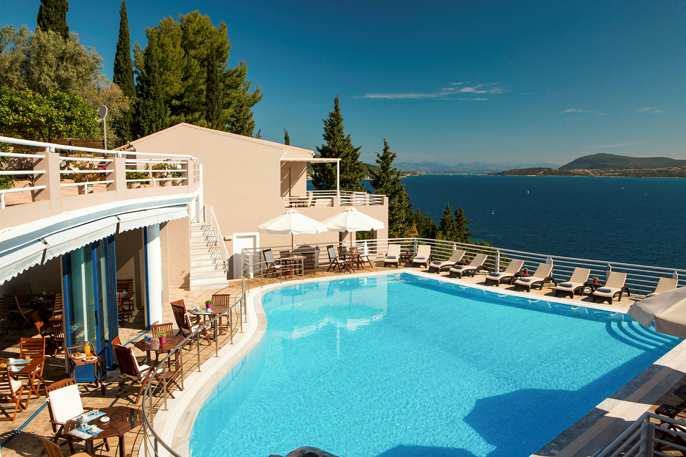 Hotelpool med liggestole og udsigt over havet. (AI-genereret tekst)