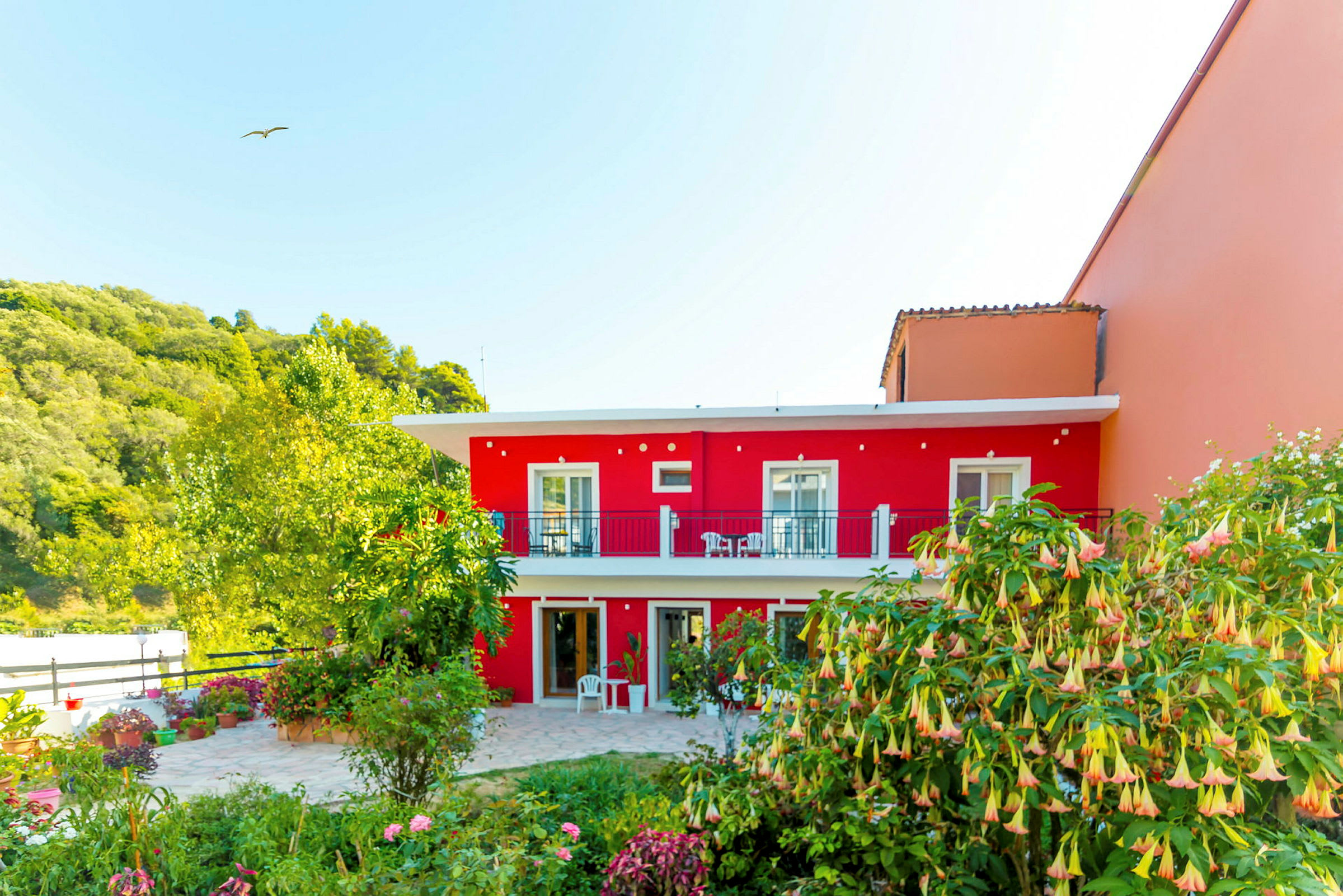 Toetagers hus med rød og orange facade, omgivet af beplantning. (AI-genereret tekst)