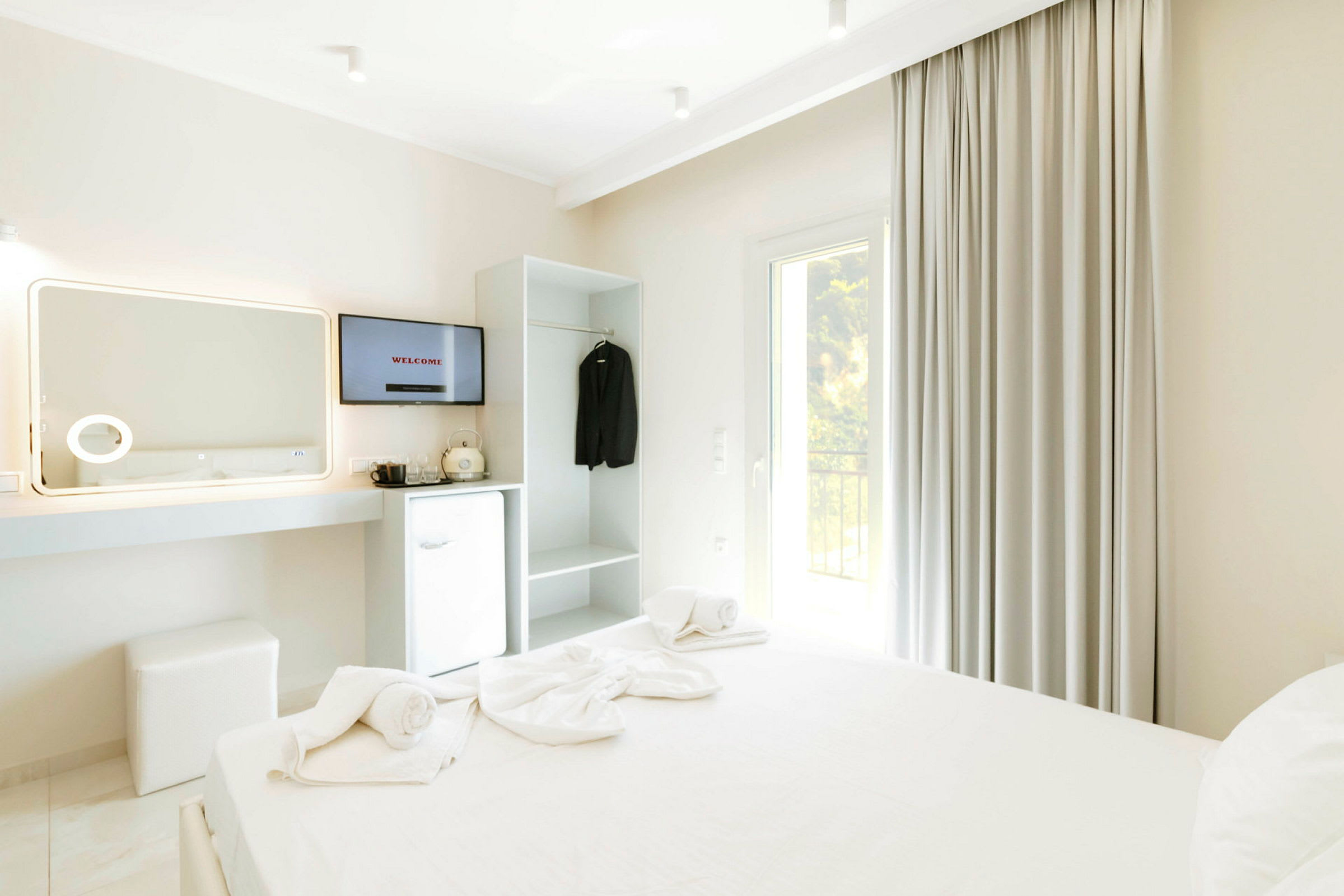 Et hotelværelse med en opredt seng, TV, køleskab og garderobe. (AI-genereret tekst)