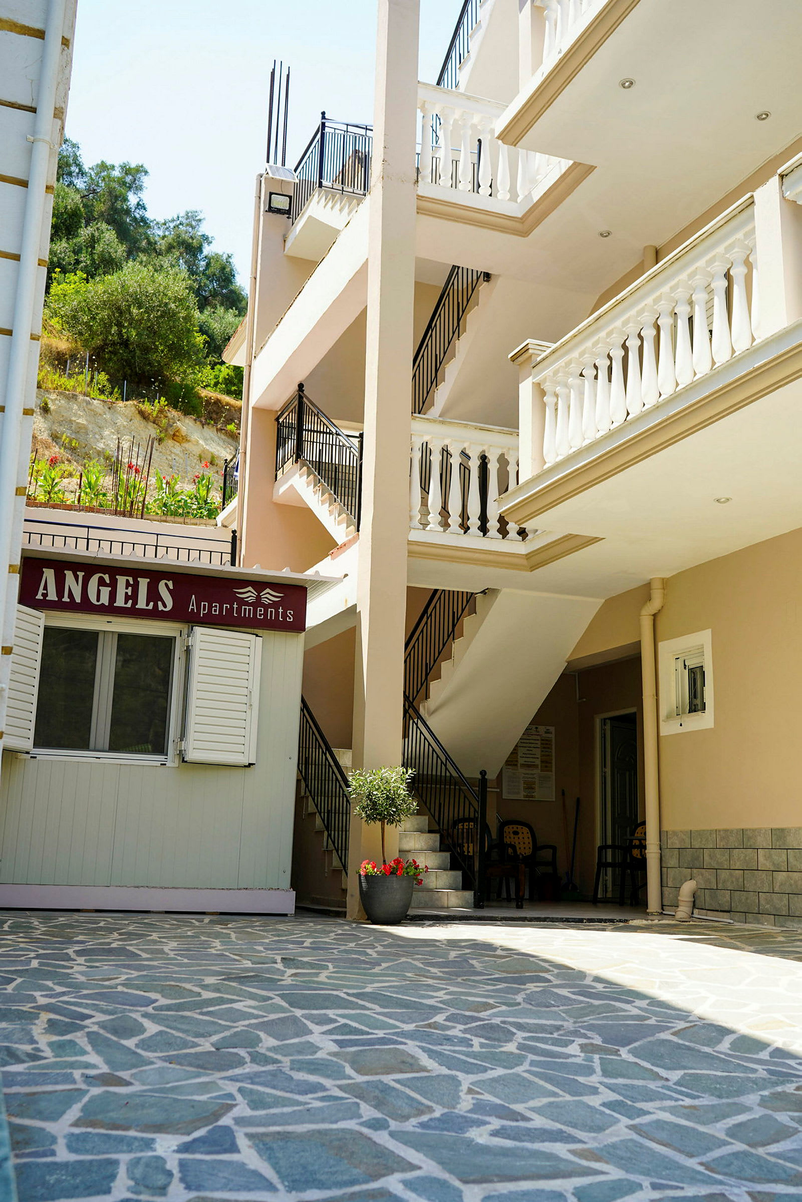 Billede af en bygning med altaner og et skilt med teksten 'Angels Apartments'. (AI-genereret tekst)