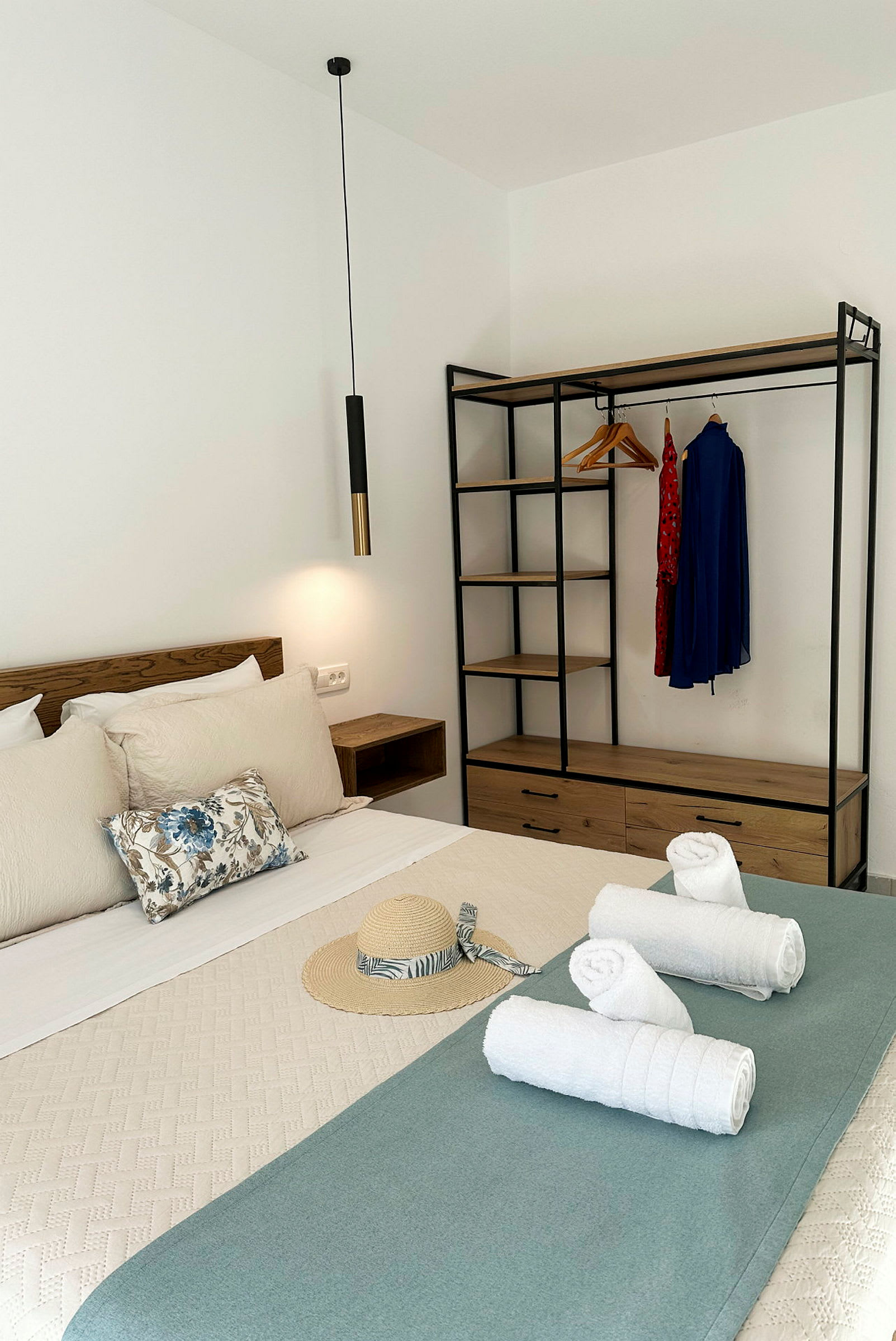 Et hotelværelse med seng, håndklæder og garderobe. (AI-genereret tekst)