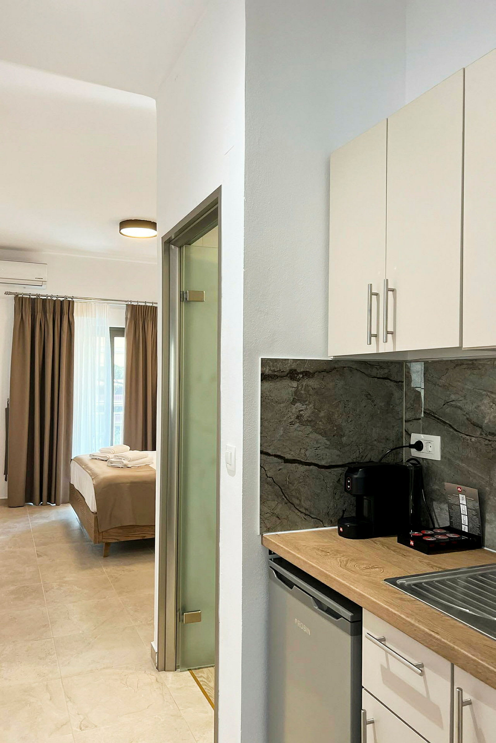 Et hotelværelse med en seng og et køkken med kaffemaskine. (AI-genereret tekst)