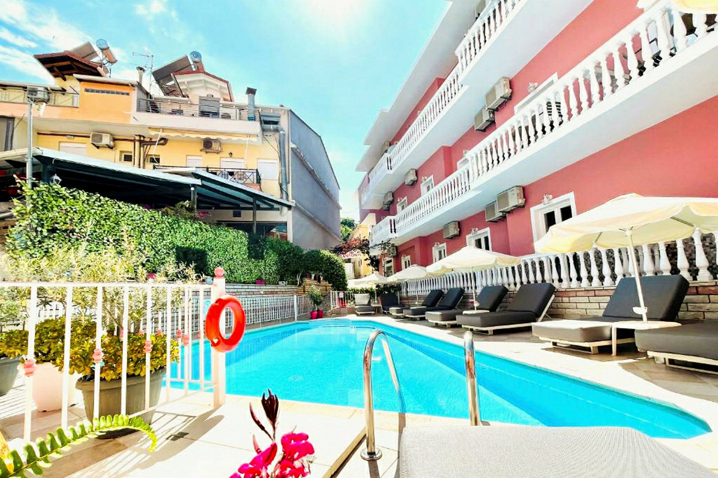 Udendørs pool ved et hotel med liggestole og parasoller. (AI-genereret tekst)