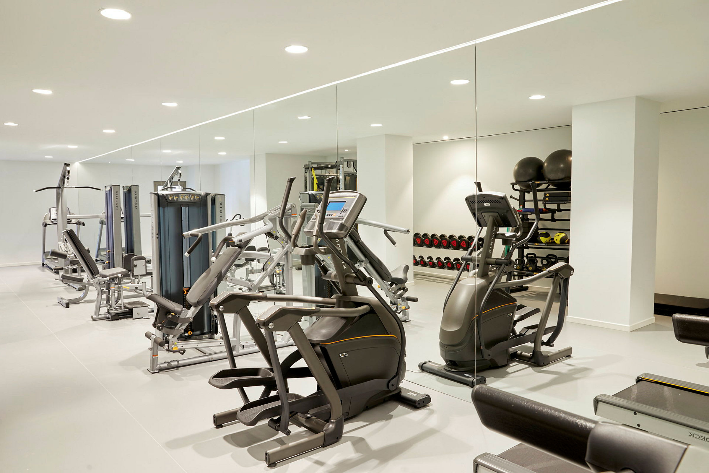 Billede af et fitnesscenter med træningsmaskiner, vægte og spejlvæg. (AI-genereret tekst)