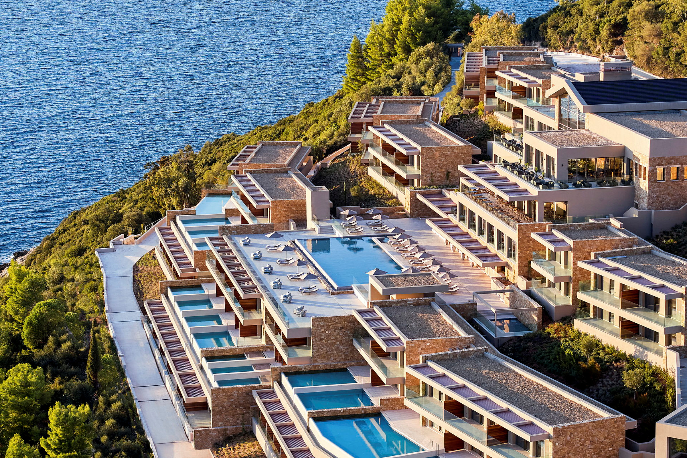 Billede af et hotelkompleks med swimmingpools, beliggende ved havet. (AI-genereret tekst)