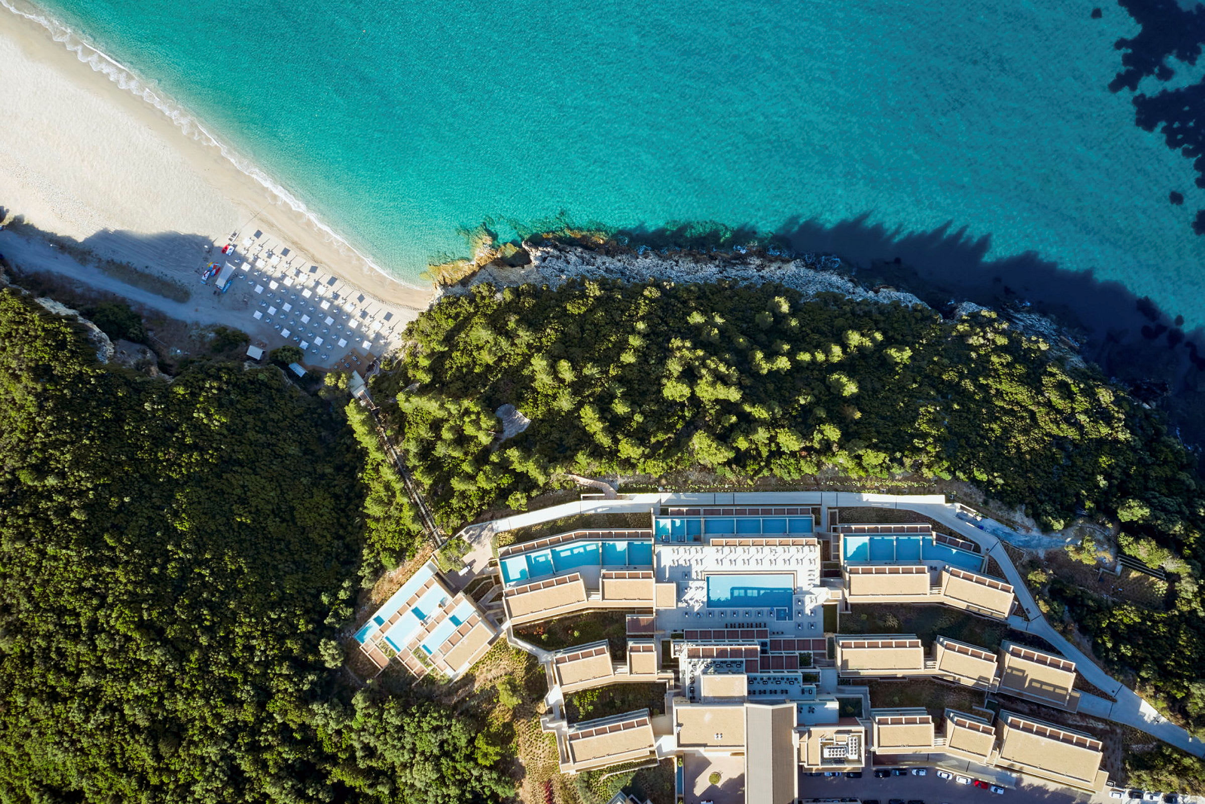 Luftfoto af et hotelkompleks ved stranden med omkringliggende vegetation. (AI-genereret tekst)