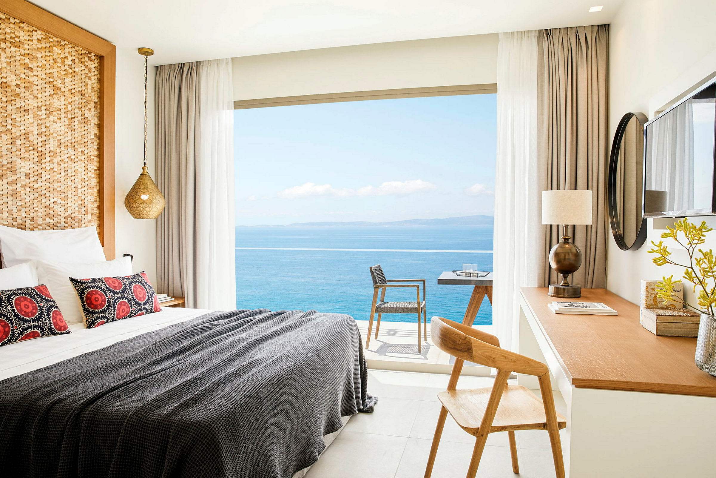 Et hotelværelse med en opredt seng, skrivebord og udsigt over havet gennem vinduet. (AI-genereret tekst)