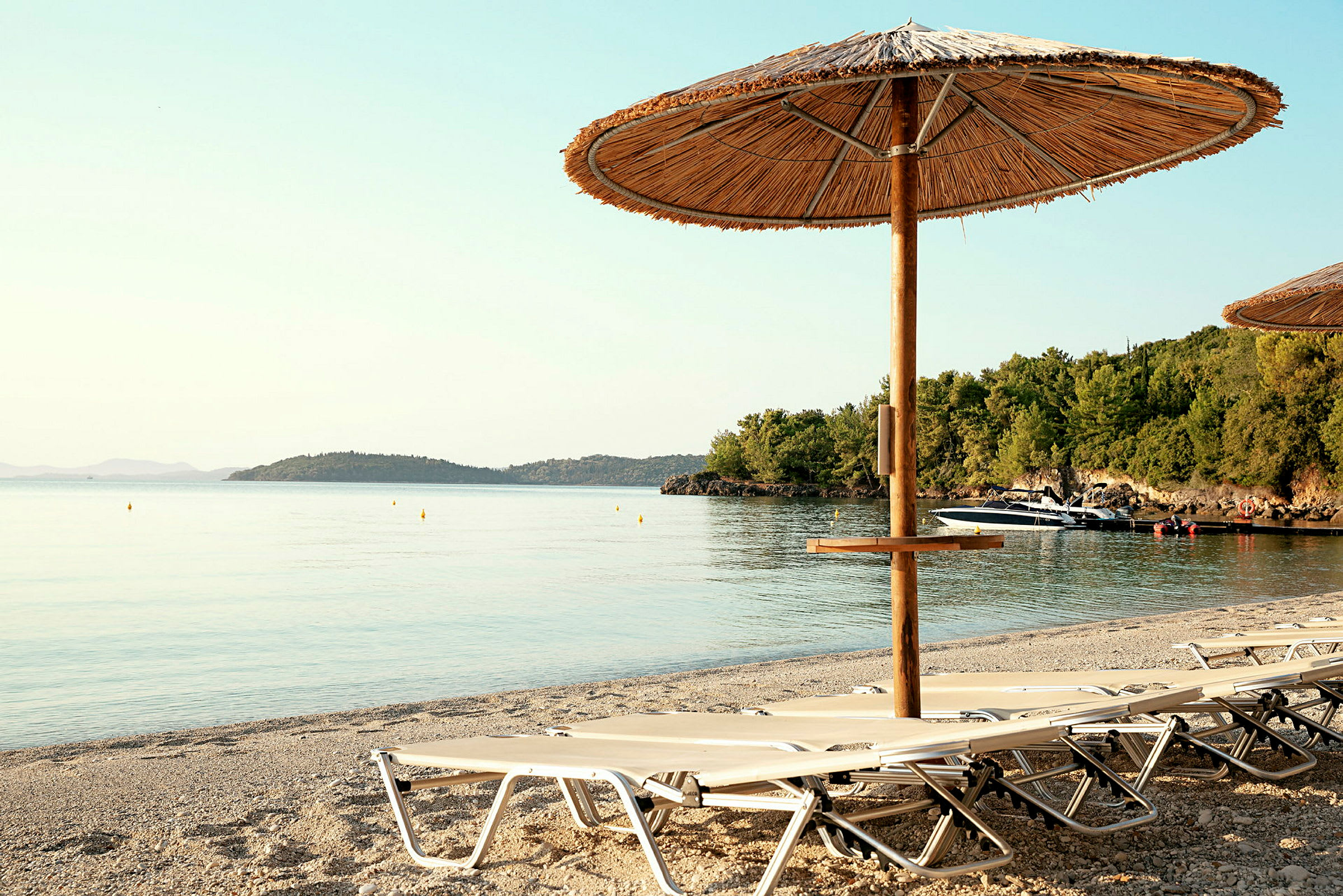 Strand med liggestole og parasol ved vandkanten. (AI-genereret tekst)