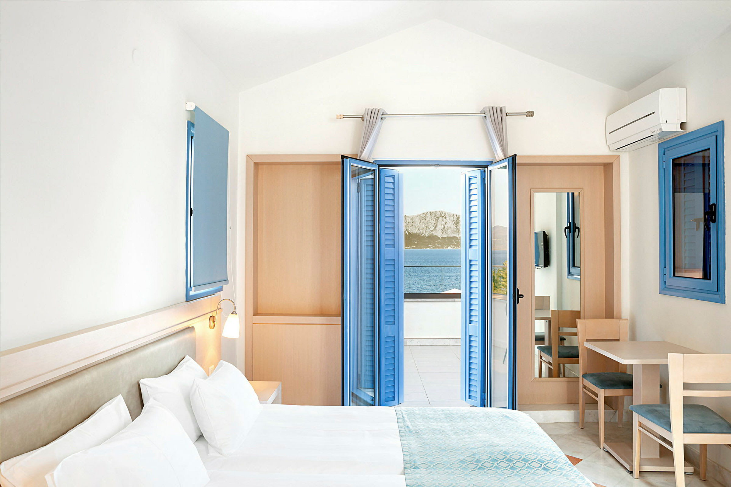 Hotelværelse med dobbeltseng og havudsigt gennem åbne blå skodder. (AI-genereret tekst)