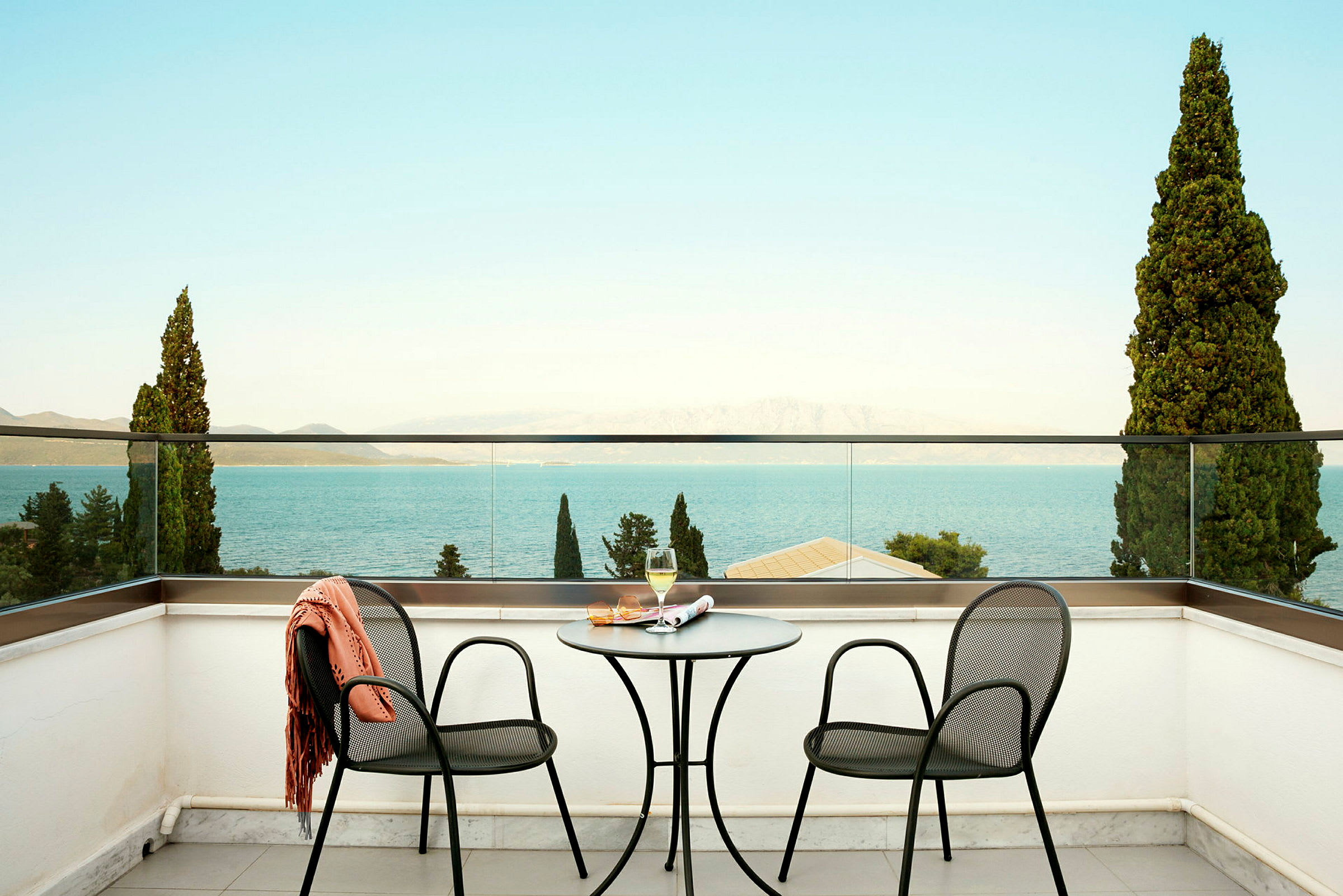 To stole og et bord på en terrasse med udsigt over havet. (AI-genereret tekst)