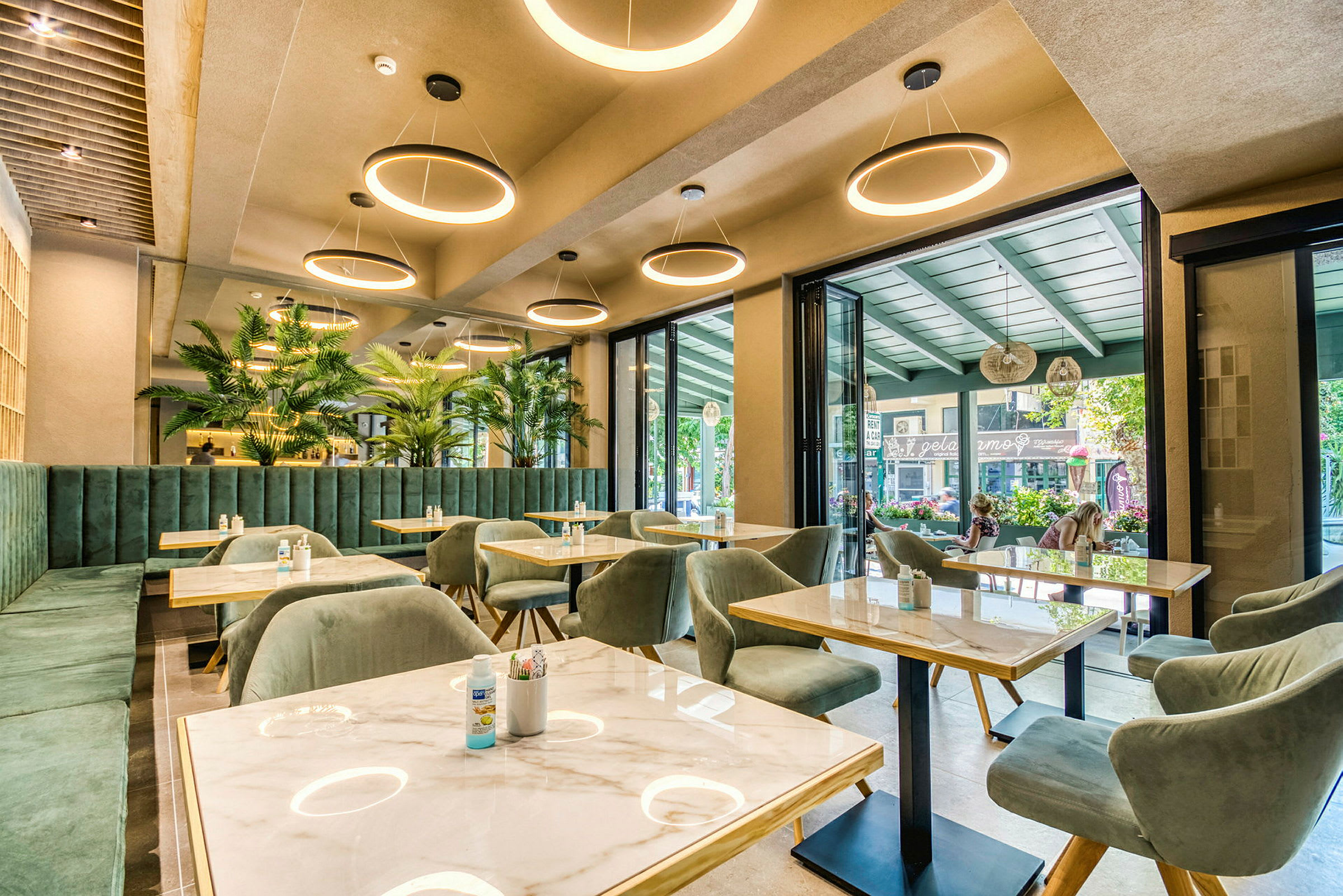 En moderne restaurant med grønne møbler og store vinduer. (AI-genereret tekst)