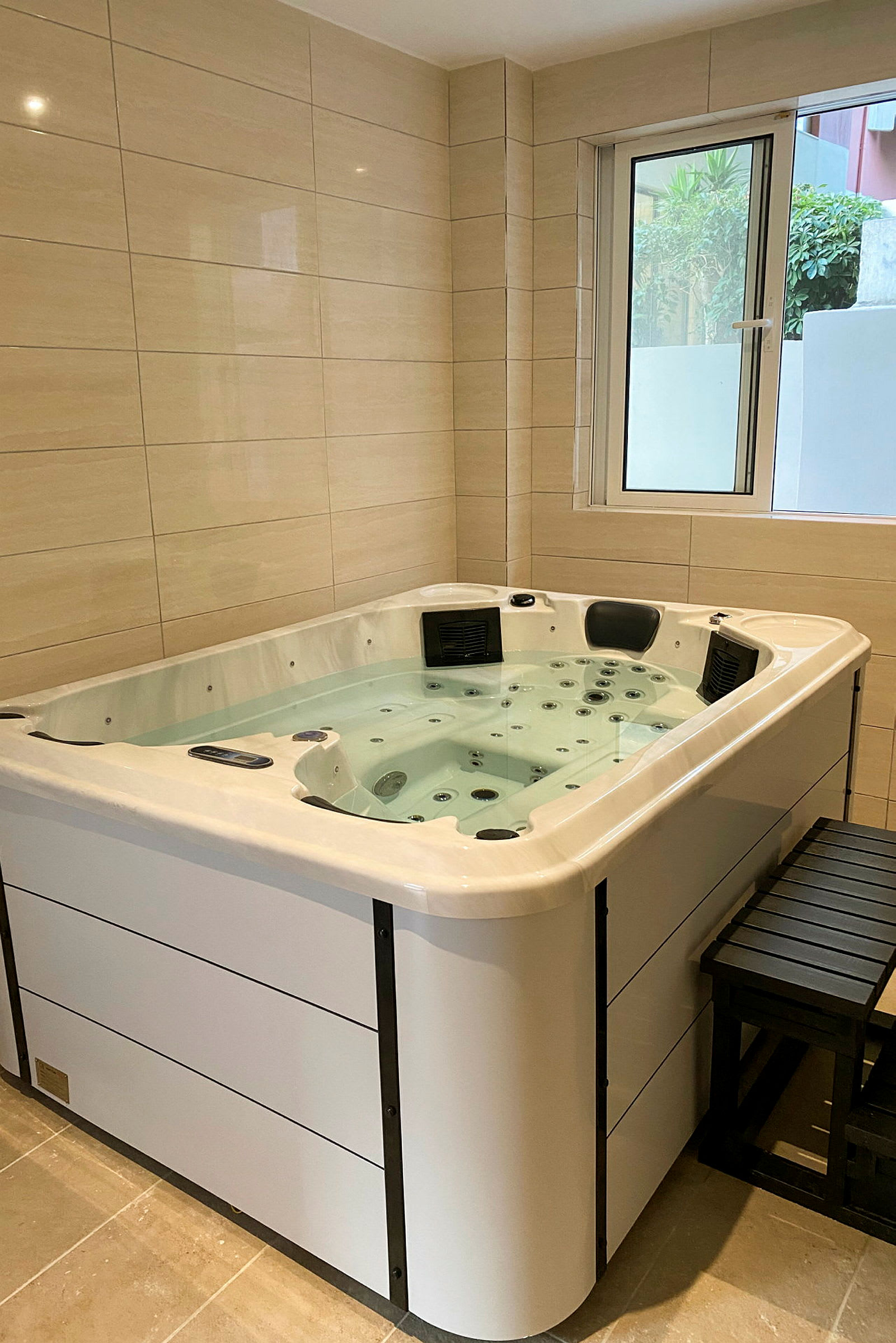 Indendørs jacuzzi med vand, placeret tæt på et vindue. (AI-genereret tekst)