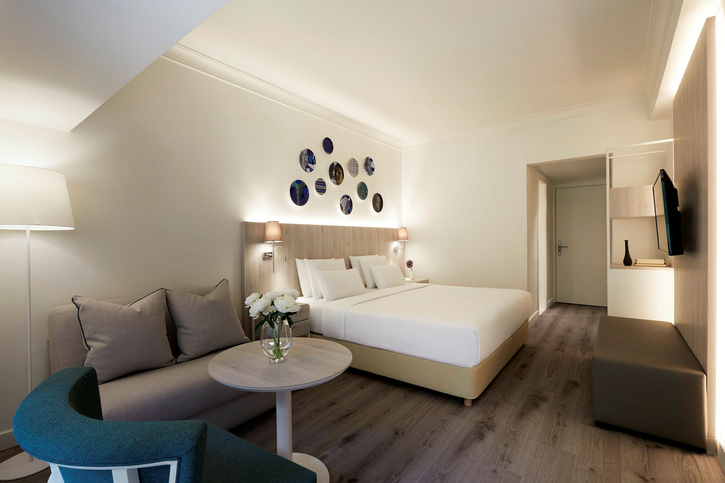Et hotelværelse med en seng, en sofa og et sofabord, dekoreret med moderne detaljer. (AI-genereret tekst)