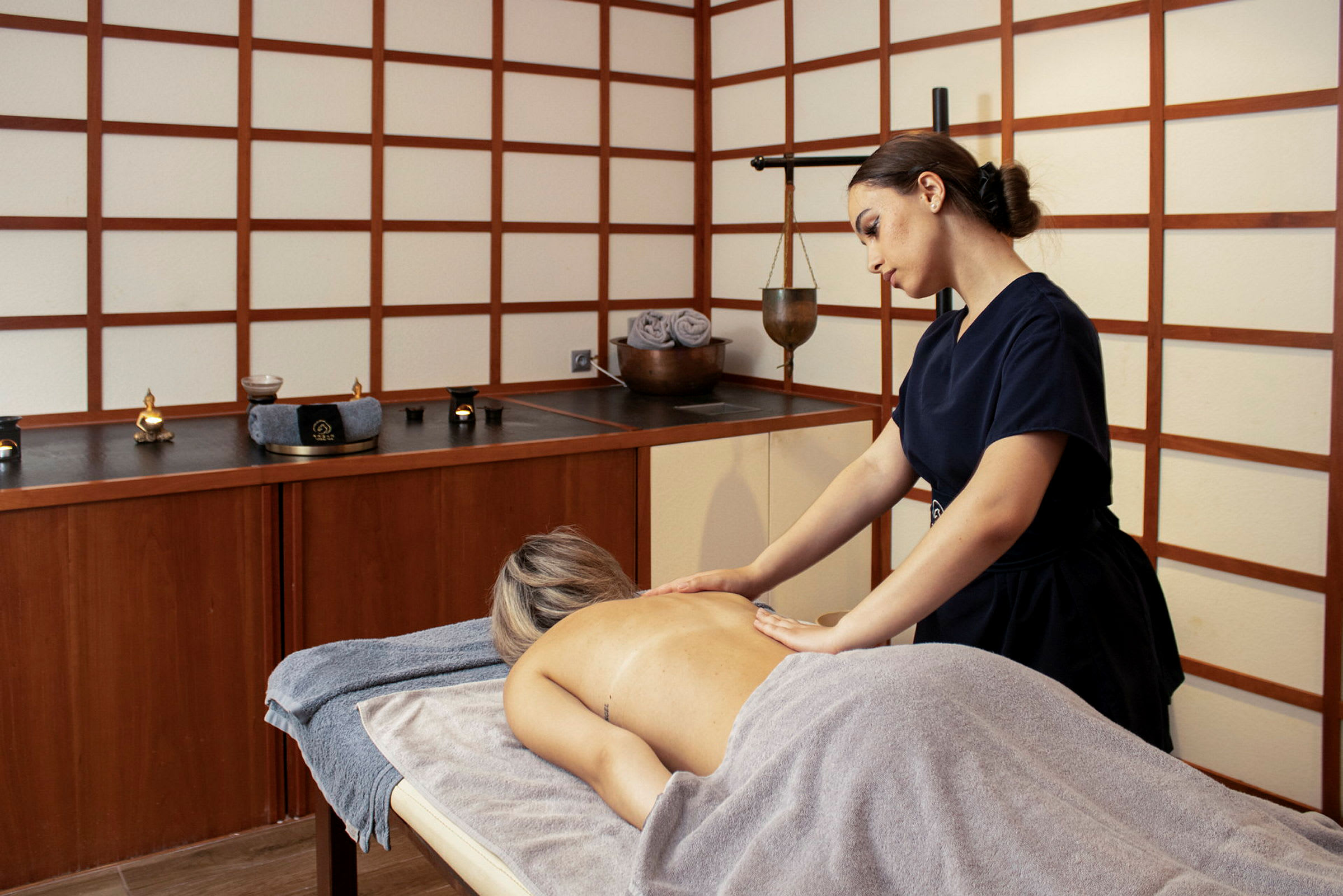 En person modtager massage på et spa med asiatisk inspireret indretning. (AI-genereret tekst)