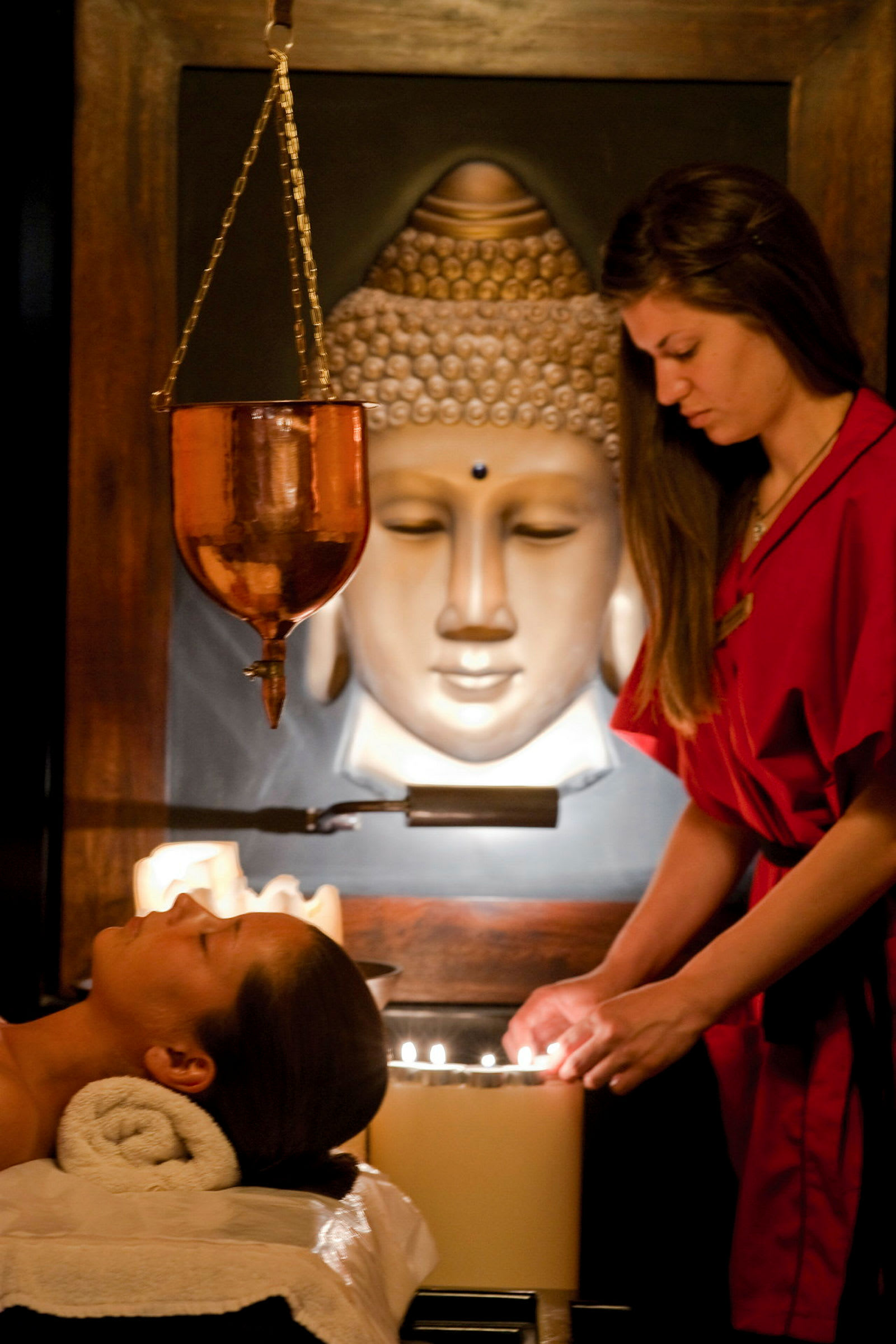 Person iført rødt terapeutudstyr justerer lys på et spa-serviceområde. (AI-genereret tekst)