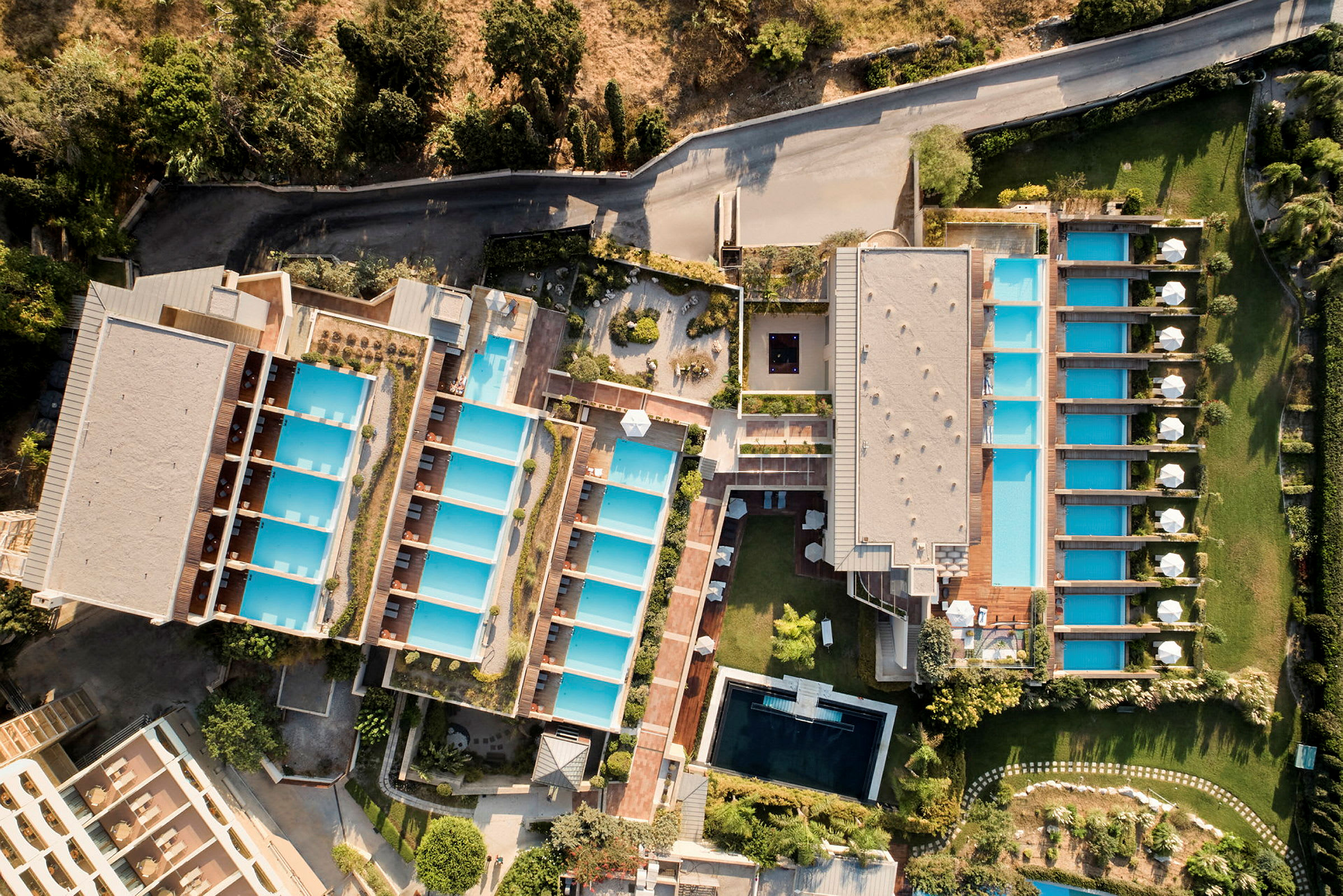 Luftfoto af et hotelområde med flere swimmingpools. (AI-genereret tekst)
