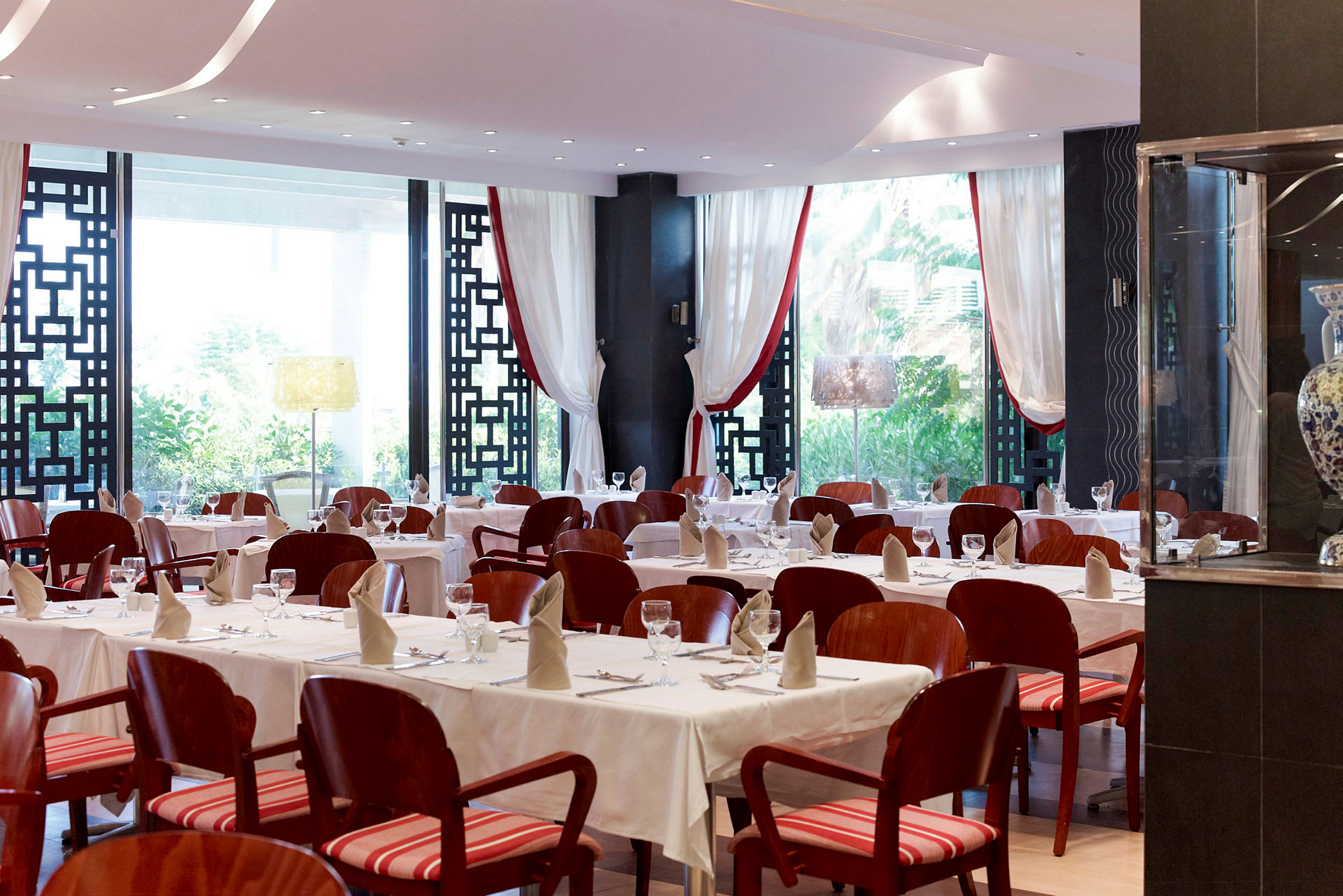 En elegant restaurant med dækkede borde og røde stole. (AI-genereret tekst)