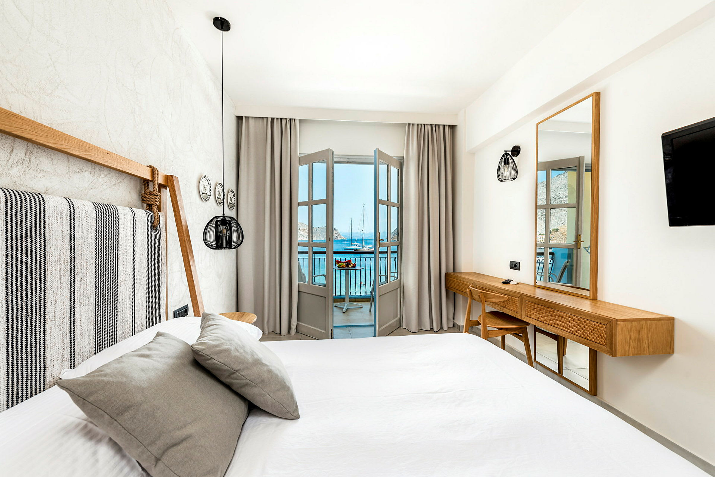 Et lyst og moderne indrettet hotelværelse med seng og udsigt over havet fra en altan. (AI-genereret tekst)