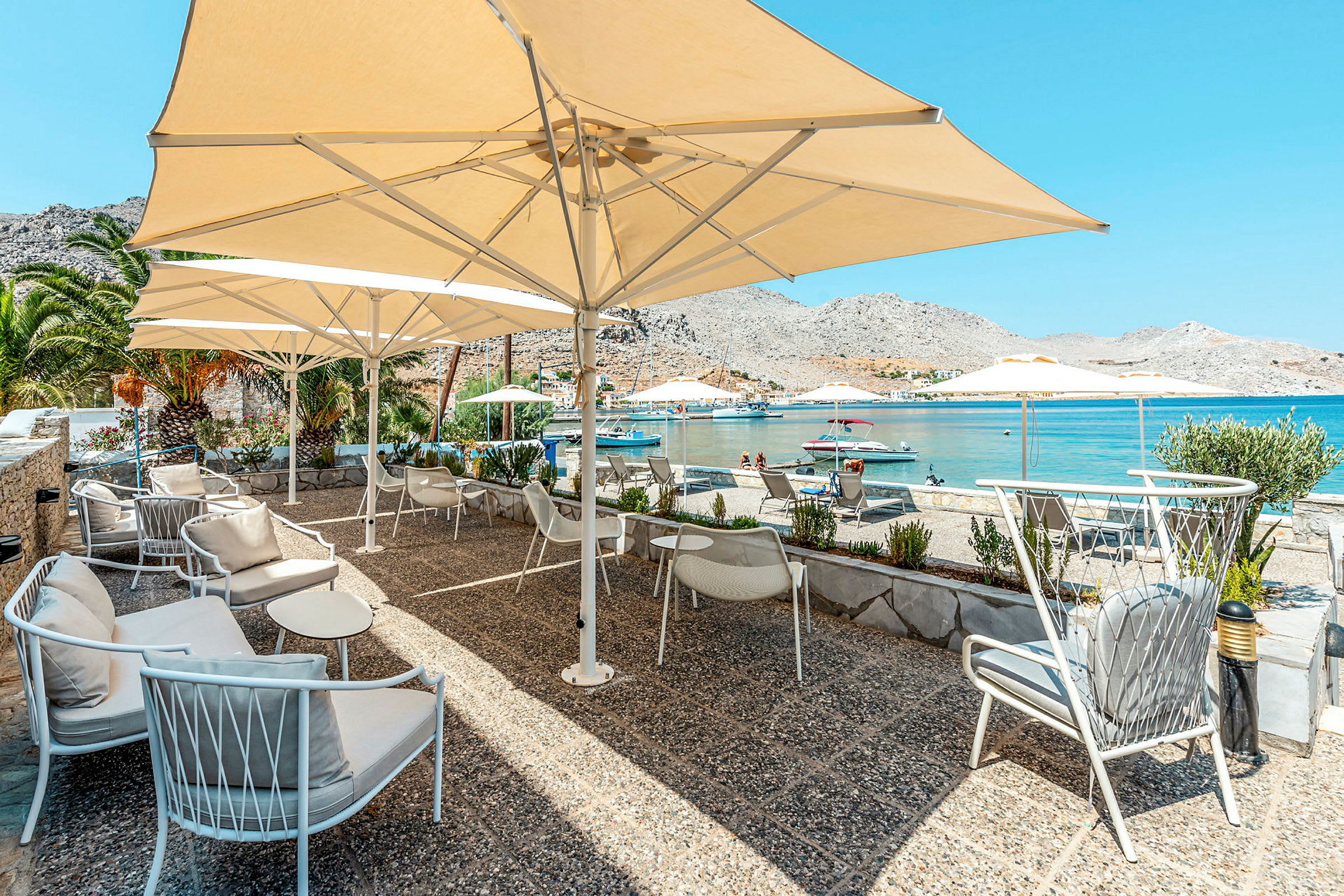 En terrasse med siddepladser og parasoller ved havet. (AI-genereret tekst)